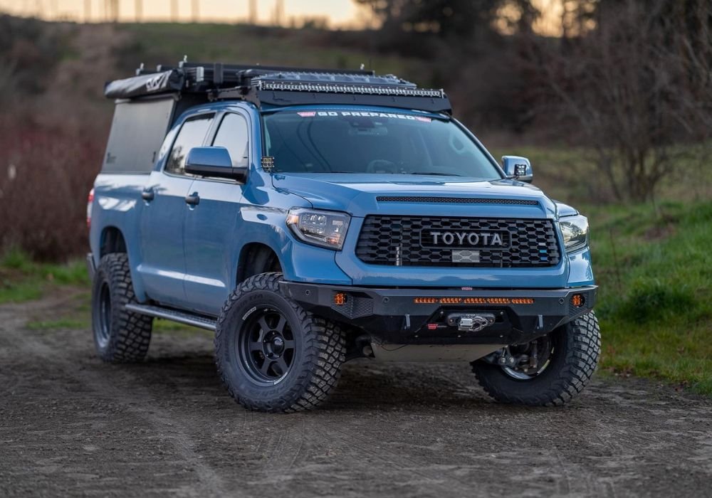 Blue Toyota pickup truck modified for off-road use on dirt path