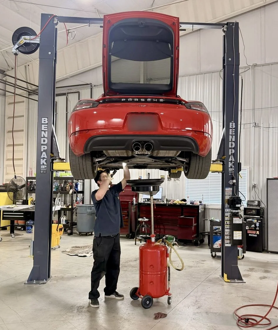 EuroSpring Autoworks tech doing an oil change on a red Porsche 718 in Castle Rock, CO.