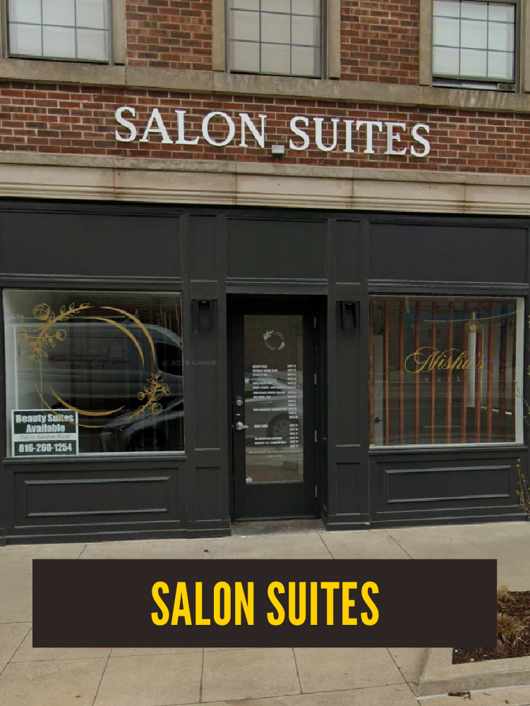 Exterior of a storefront with a sign reading 'Salon Suites' above the entrance, black framed windows, and a black door in the center, with a smaller sign in the left window offering beauty suites and a phone number.  Westport East.