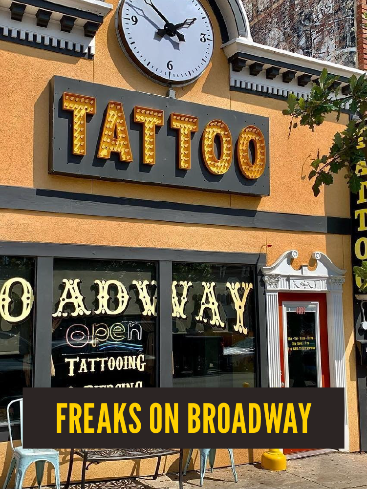  storefront with a large clock, bright yellow marquee sign reading 'TATTOO,' and a window displaying signs for a tattoo shop named 'O'ADMISSION' that is open, located on Broadway.  Westport East.