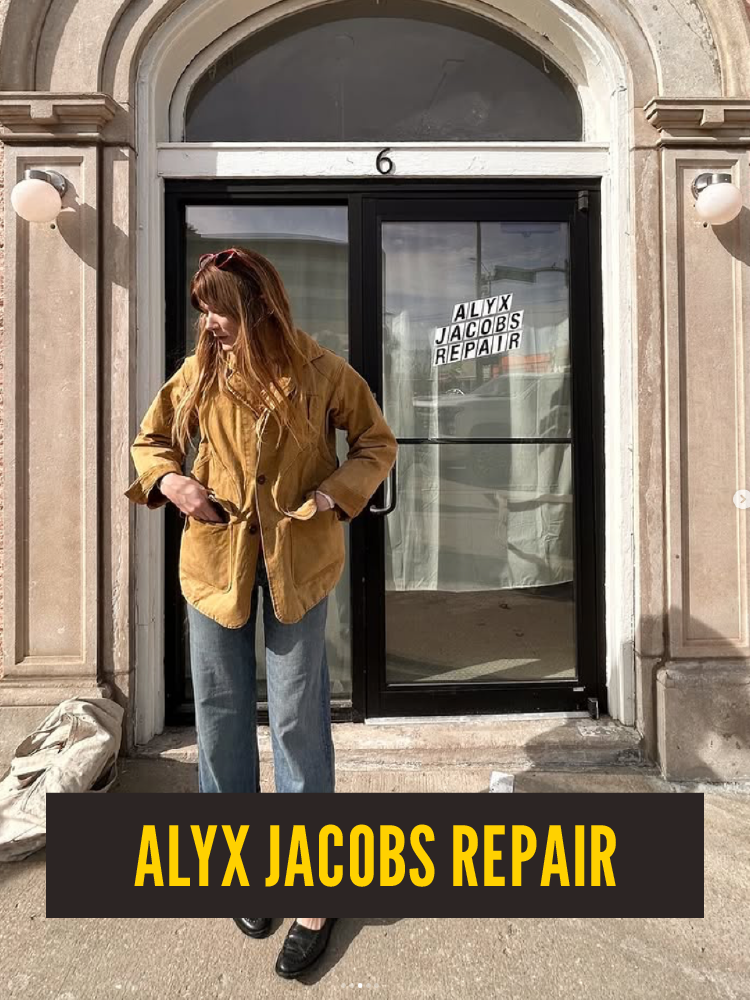 A woman in a tan jacket and jeans standing outside a building with a sign that says "ALYX JACOBS REPAIR" on the door.  Westport East.