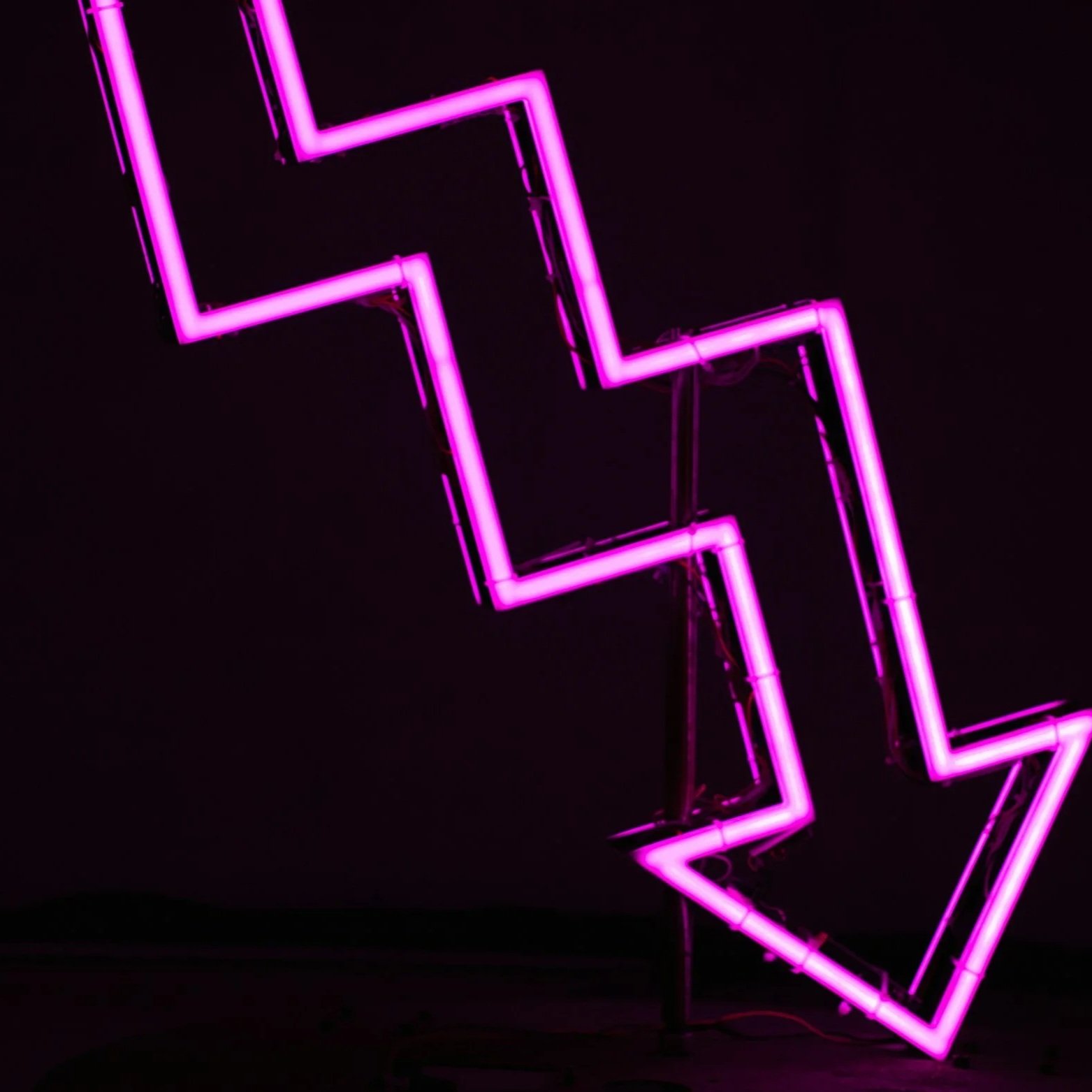 Neon pink lightning bolt signs against a dark background.