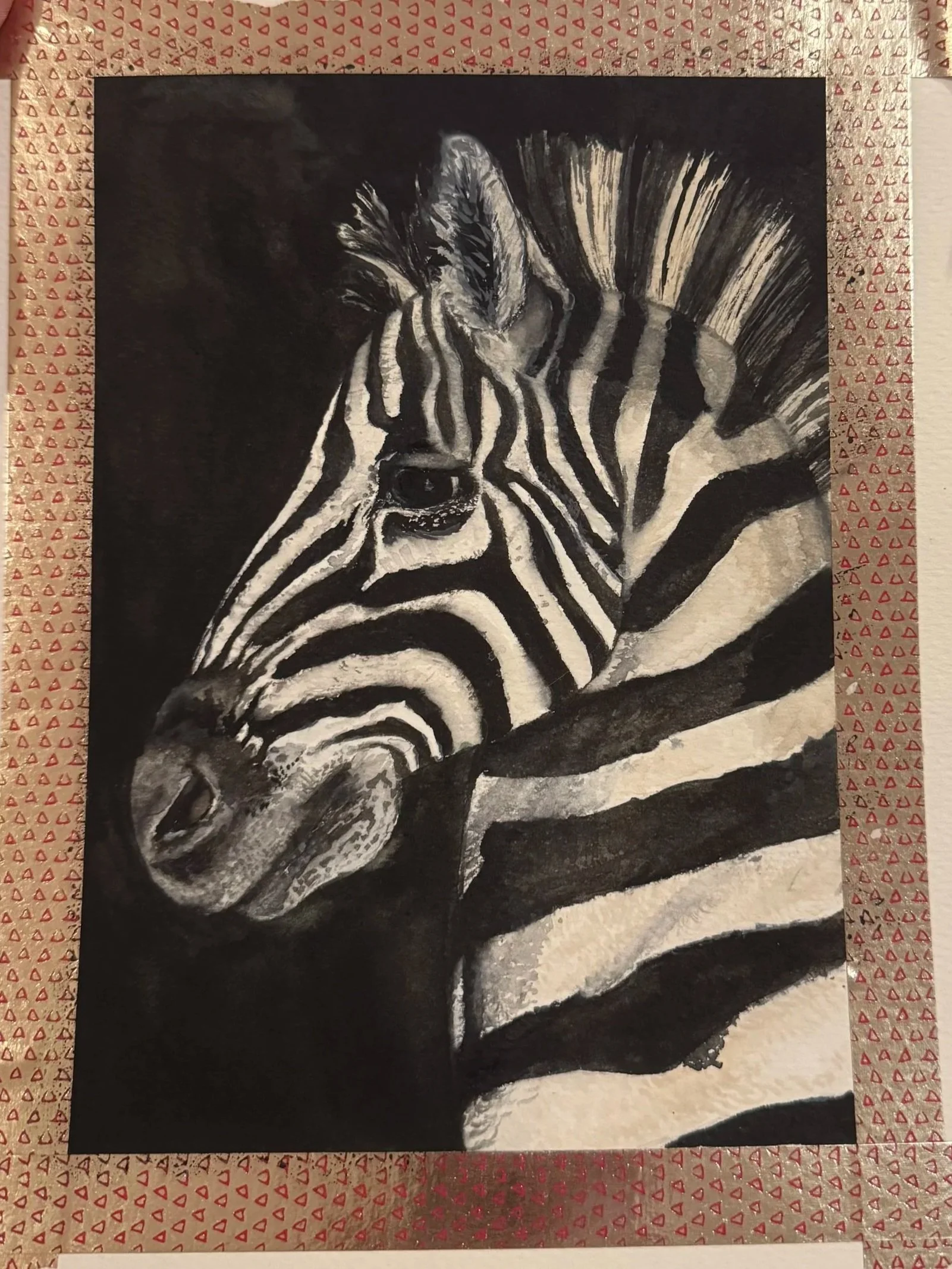 A black and white painting of a zebra's face and upper body, with distinctive zebra stripes, framed with decorative red and white triangular patterned border.