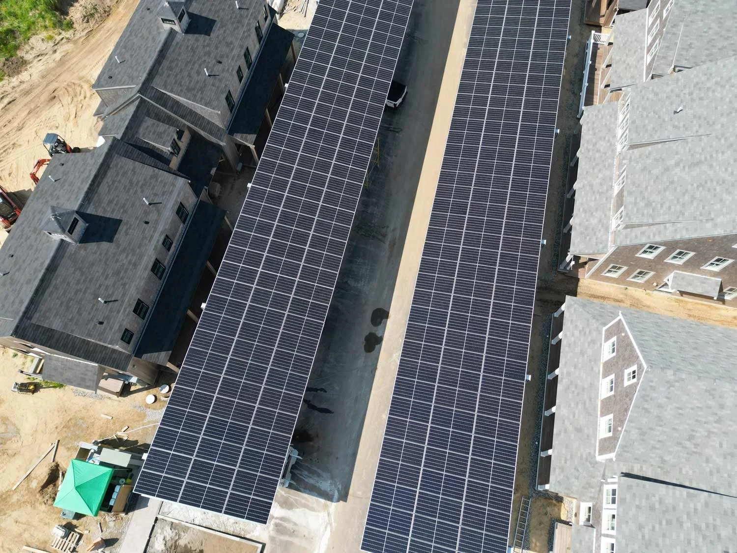 Aerial view of residential buildings with solar panels on roofs and a construction site nearby.