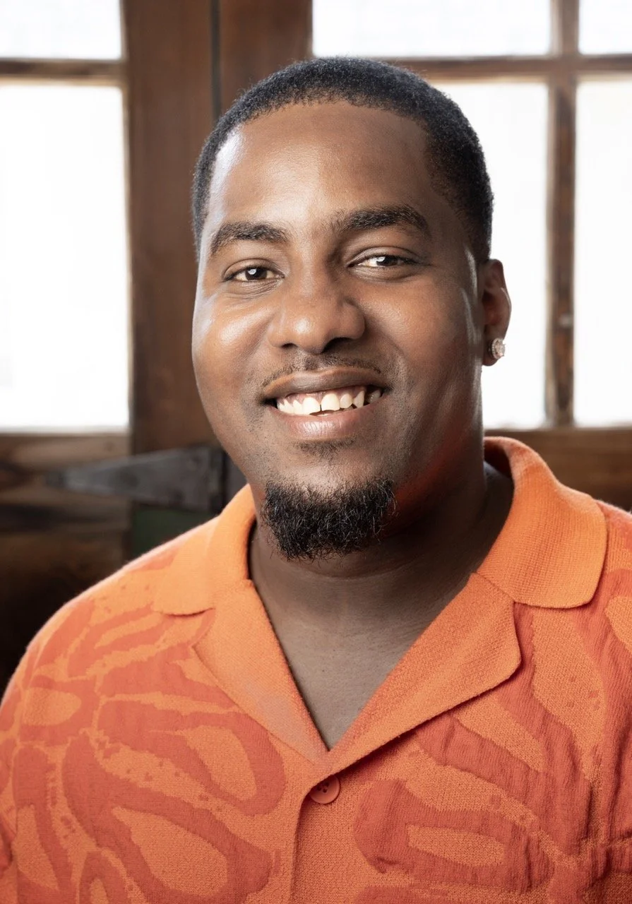 Javed Frazer wearing an orange shirt smiling at the camera