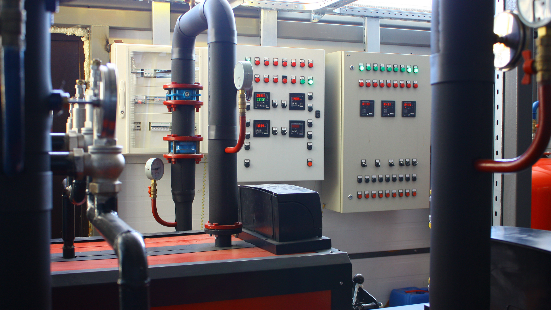 Panel de control eléctrico con interruptores y tubos en un entorno industrial.