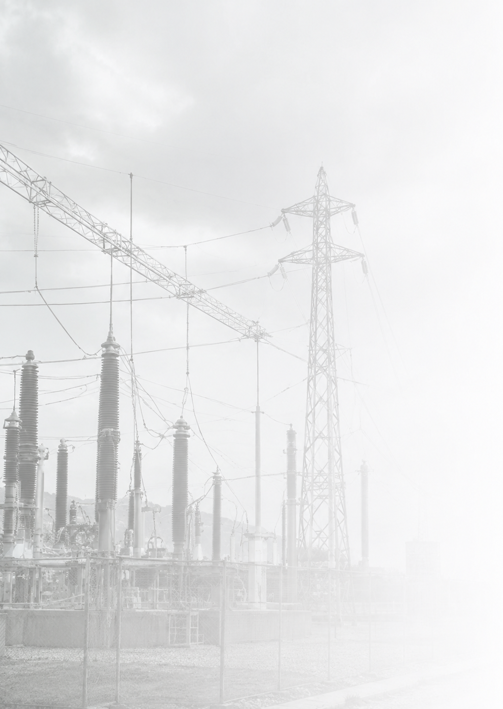 Electric power substation with transmission towers and wires, under cloudy sky.