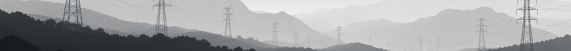Silhouettes of mountains and multiple power lines with tall transmission towers stretching across the landscape