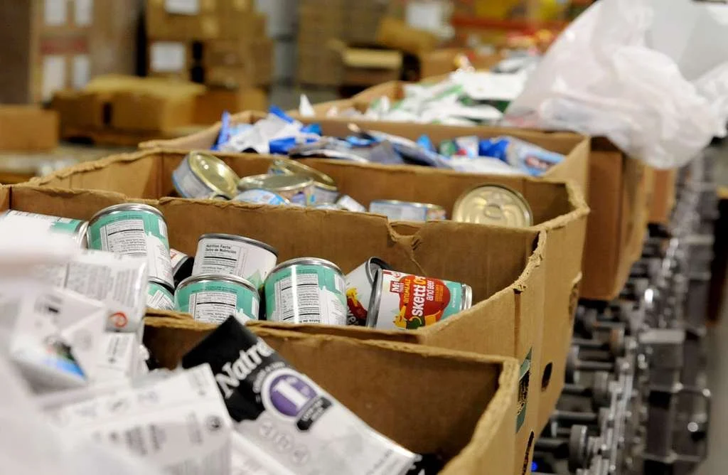 Cardboard boxes filled with canned food in a warehouse or storage area.