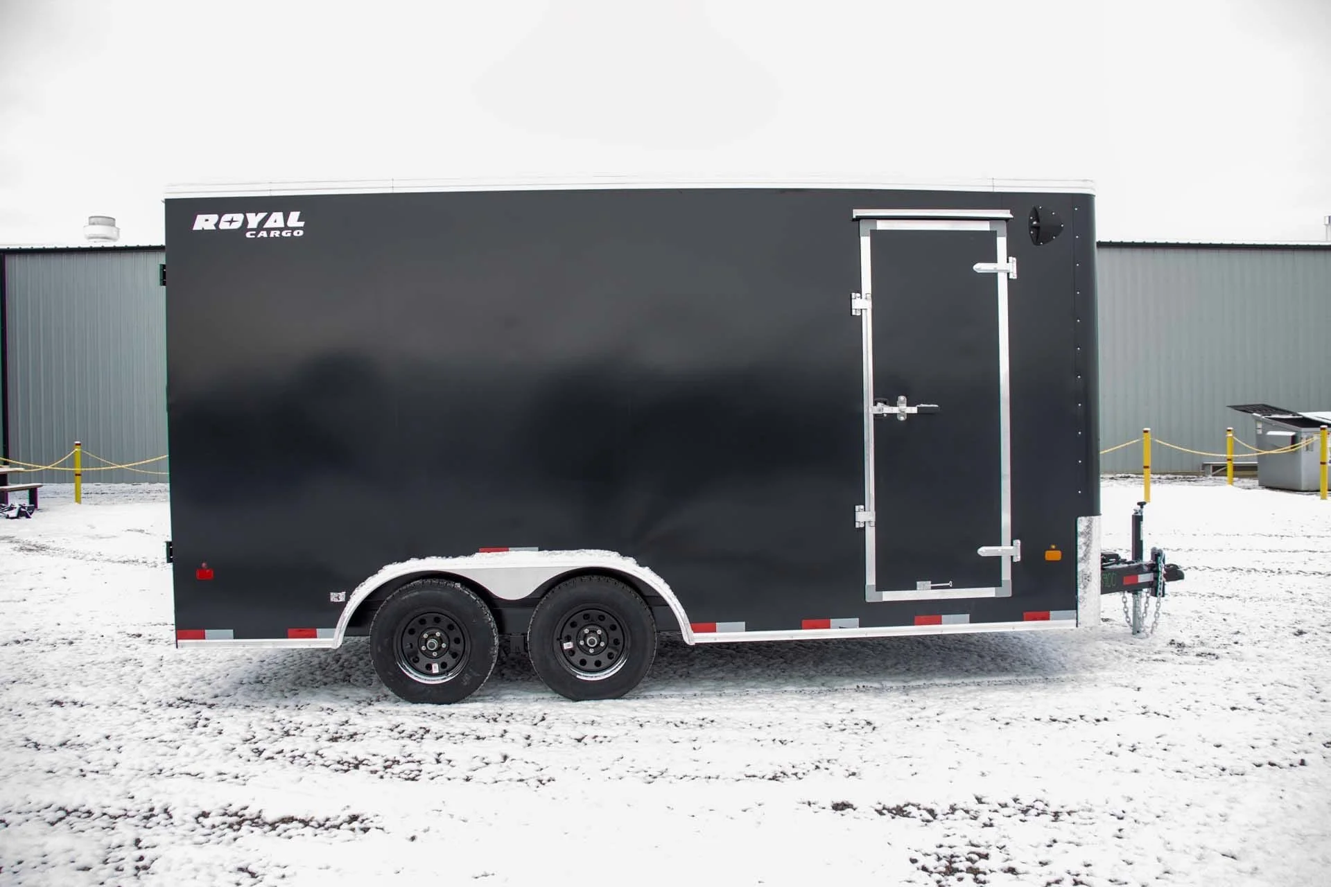Black cargo trailer with double axle parked on snowy ground, with the words "Royal Cargo" on the top left corner.