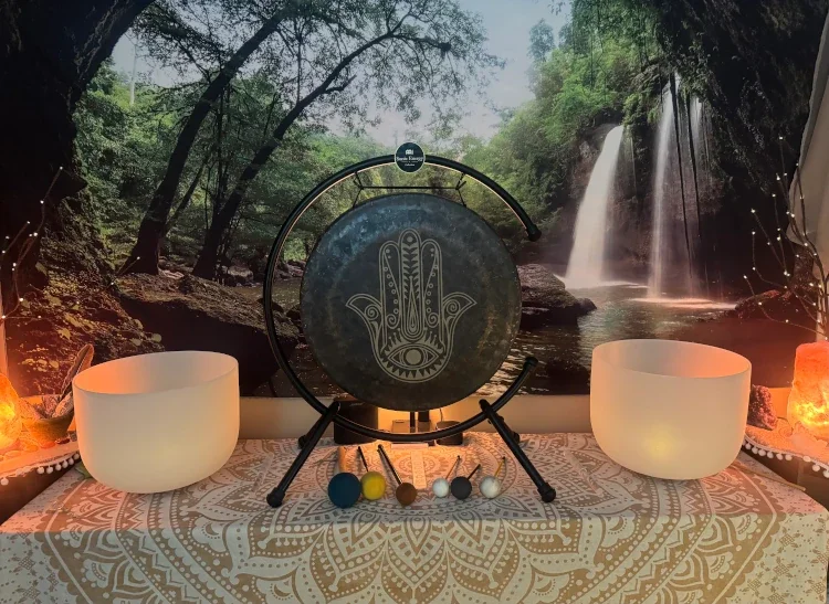 Decorative setup with musical instruments and singing bowls in front of a nature-themed backdrop featuring a waterfall and trees.