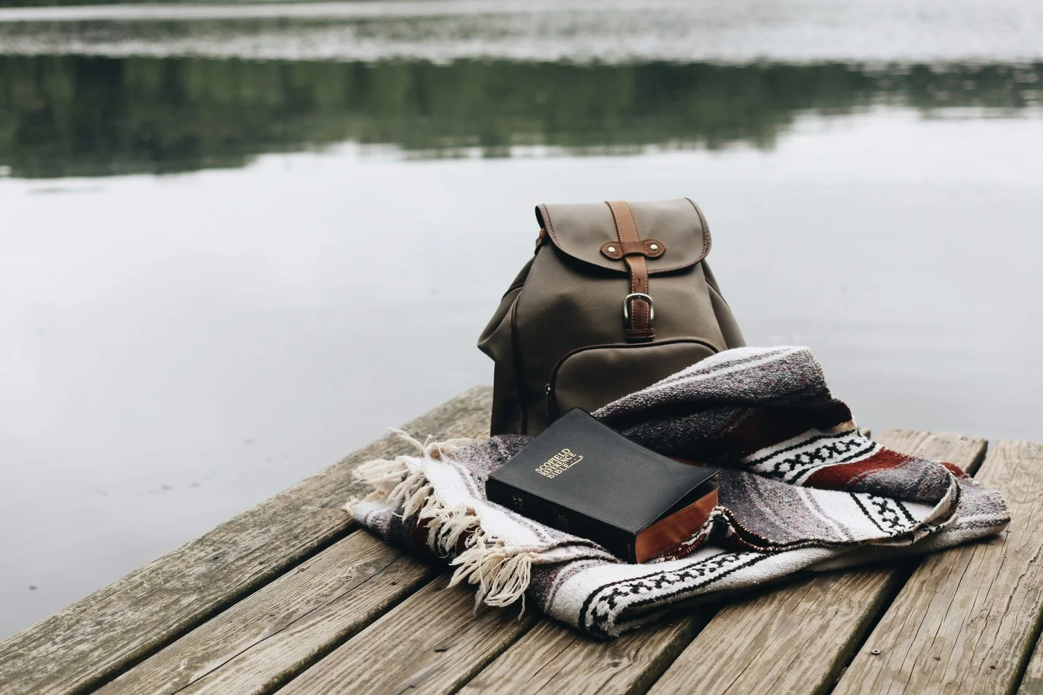 backpack and blanket near a pond