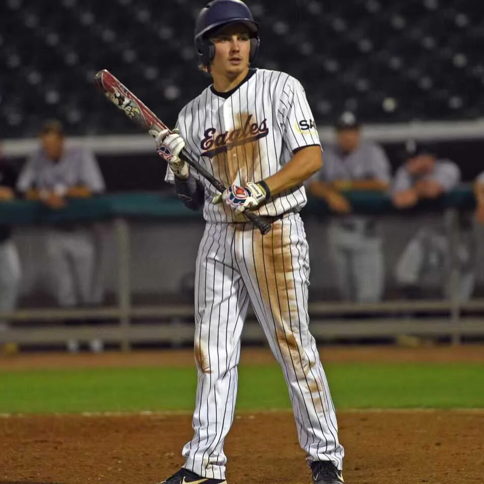 A baseball player in a white pinstripe uniform with 'Eagles' written on the front, wearing a helmet, holding a bat, and standing on a baseball field.