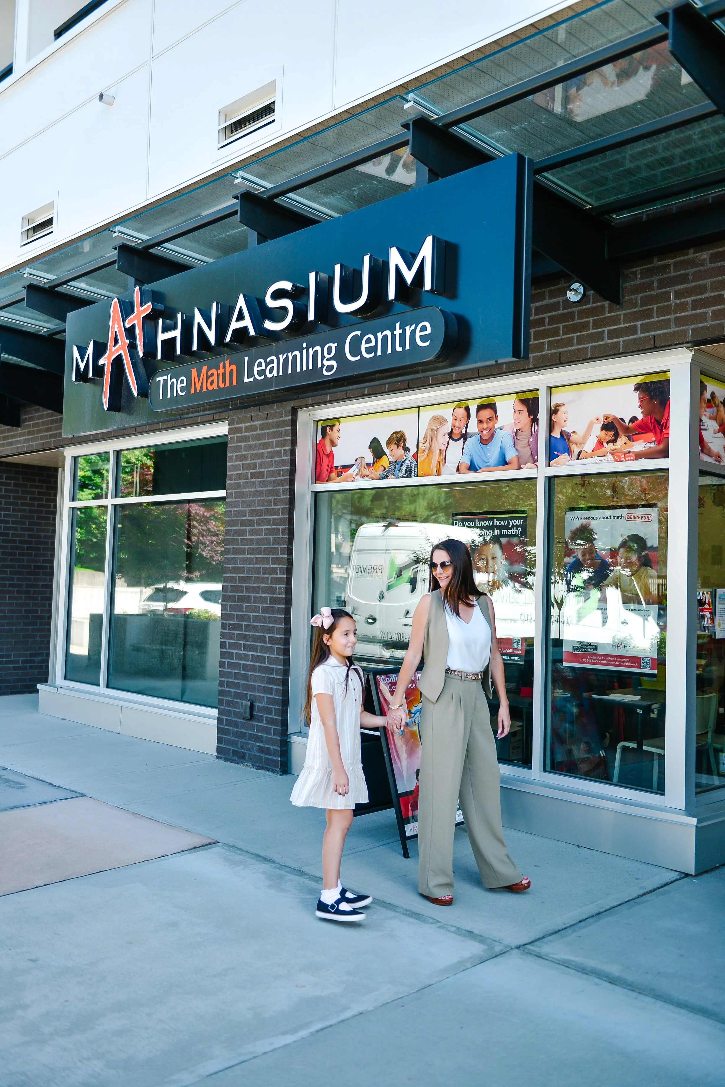 Danielle and her daughter standing on the sidewalk outside a Mathnasium learning center, holding hands.
