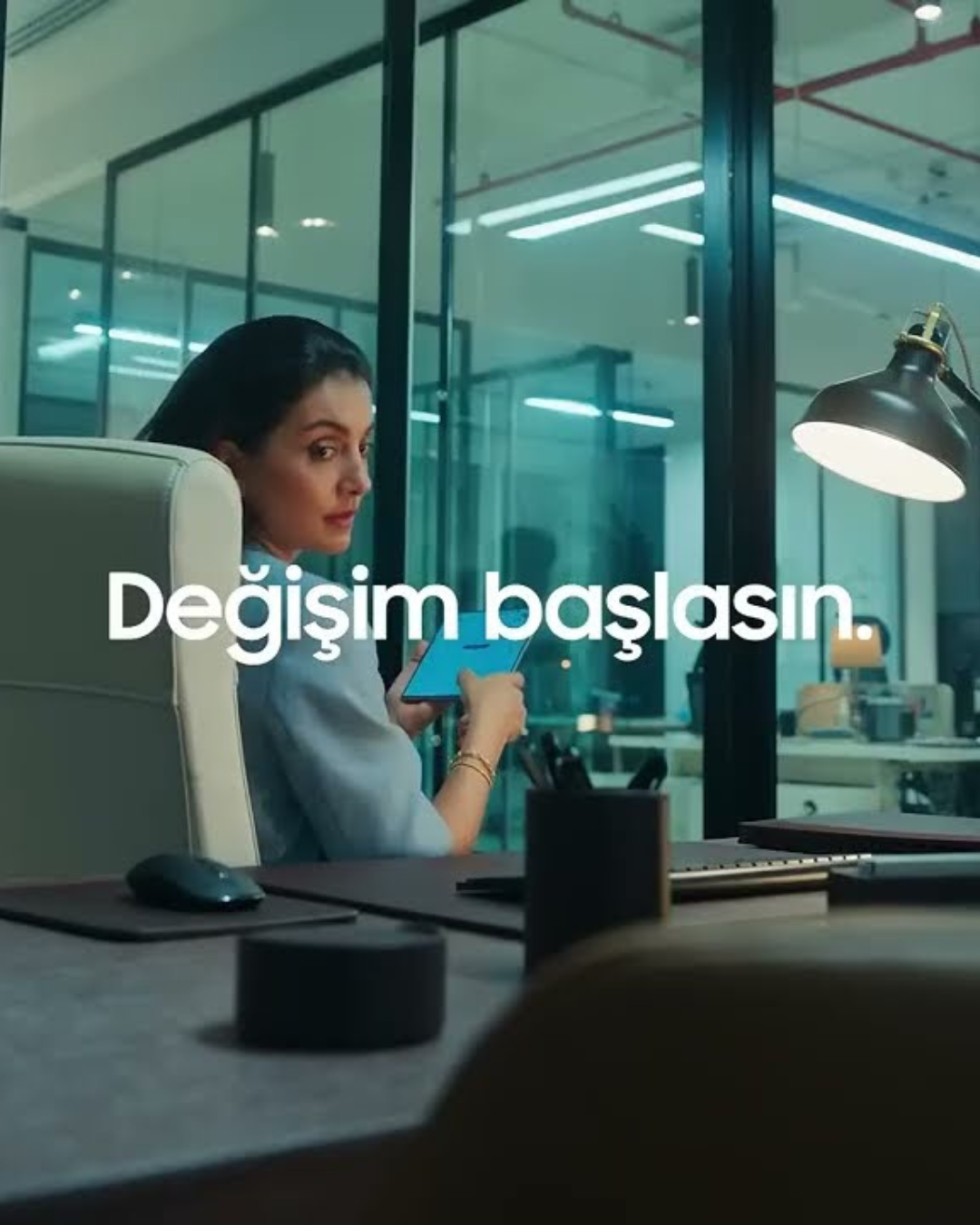 A woman in an office chair using a tablet, with a modern office background and the text 'Değişim başlasın' overlaid.