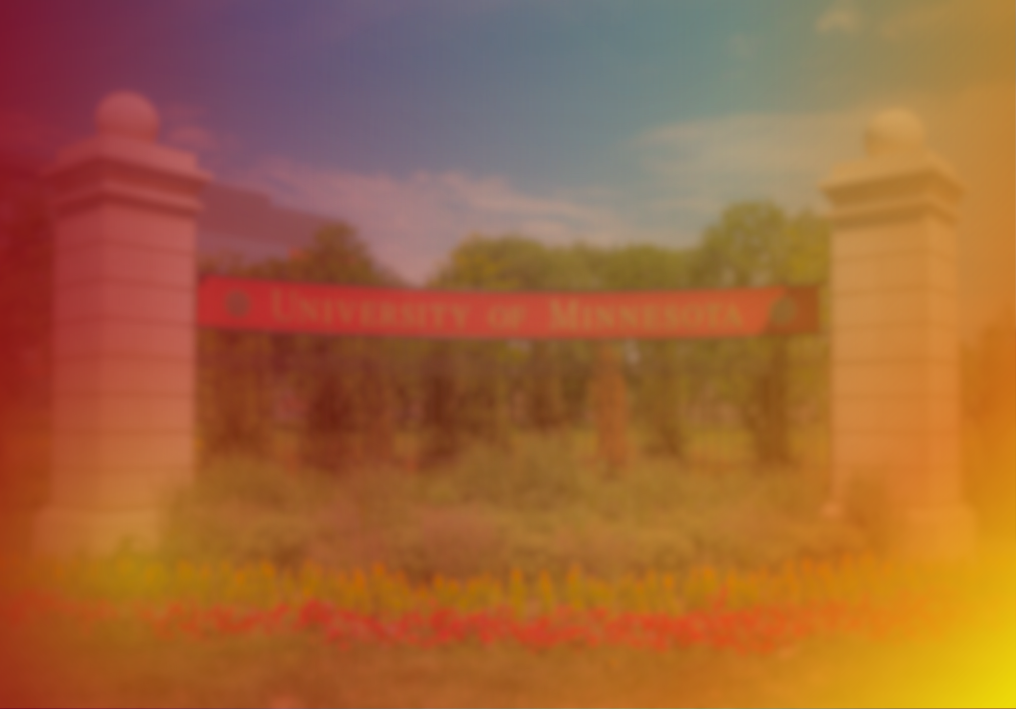 Blurred image of an entrance gate with the inscription 'University of Minnesota' on the red arch, flanked by two white pillars and green trees in the background.