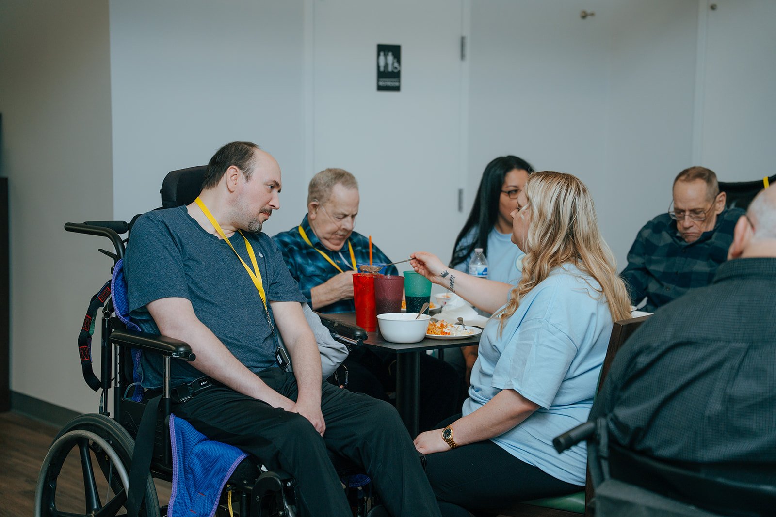 A group of people with disabilities dine together at a table. They share a warm meal at Avielle Haven, offering supportive long-term residential care, specialized memory care, and assisted living in Midland, MI.