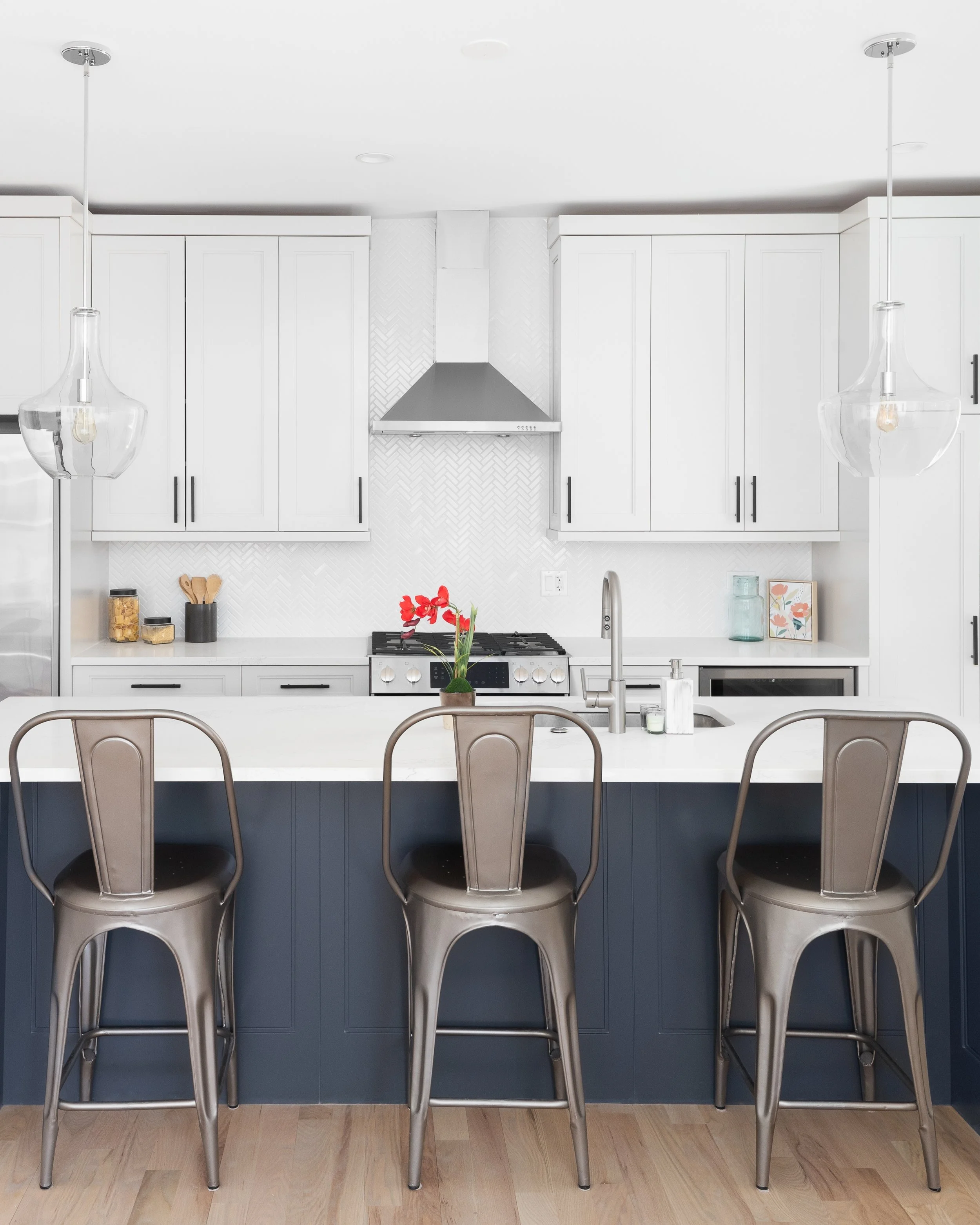 Modern white kitchen design with navy island and pendant lights — GTA