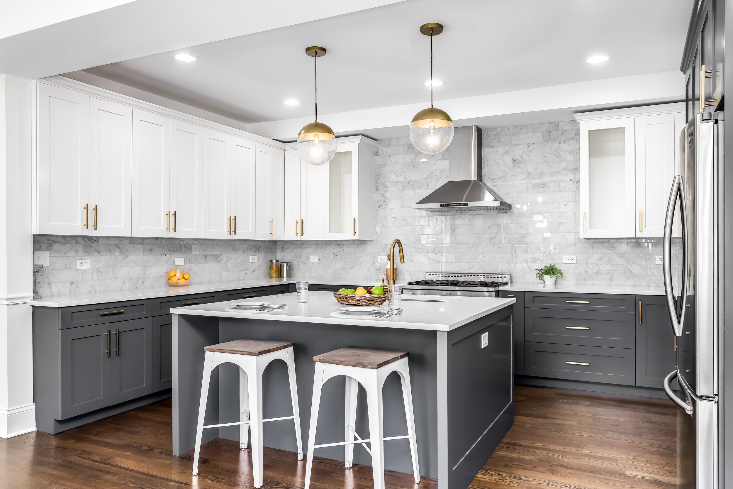 Two-tone kitchen cabinets white and gray with marble backsplash