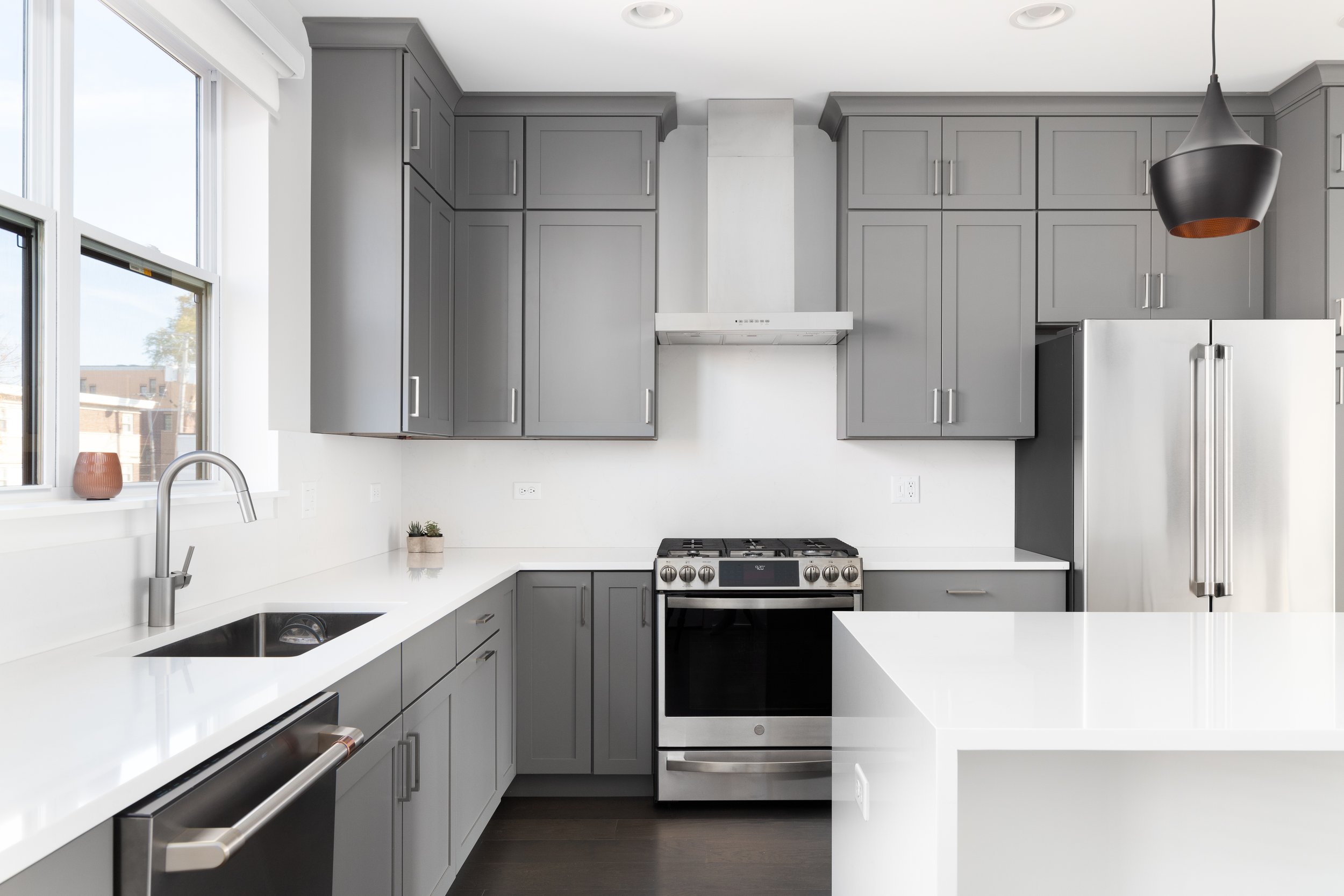 Gray shaker kitchen cabinets with white countertops.