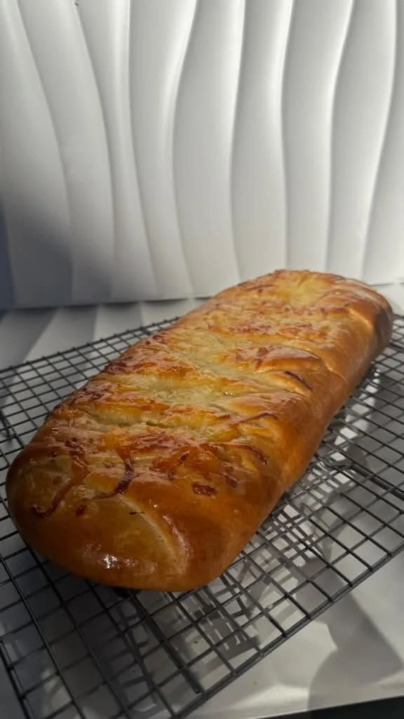 Pan de queso dorado y crujiente sobre una rejilla de enfriamiento.