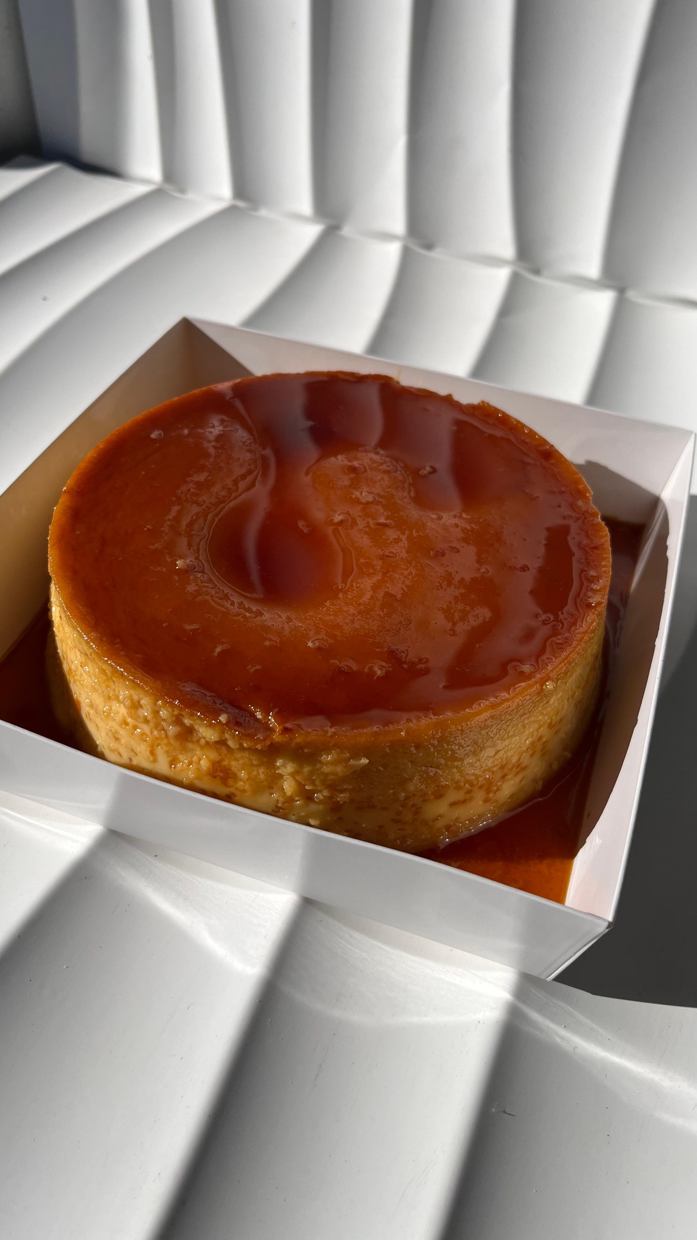 Pastel de flan con caramelo en caja blanca.