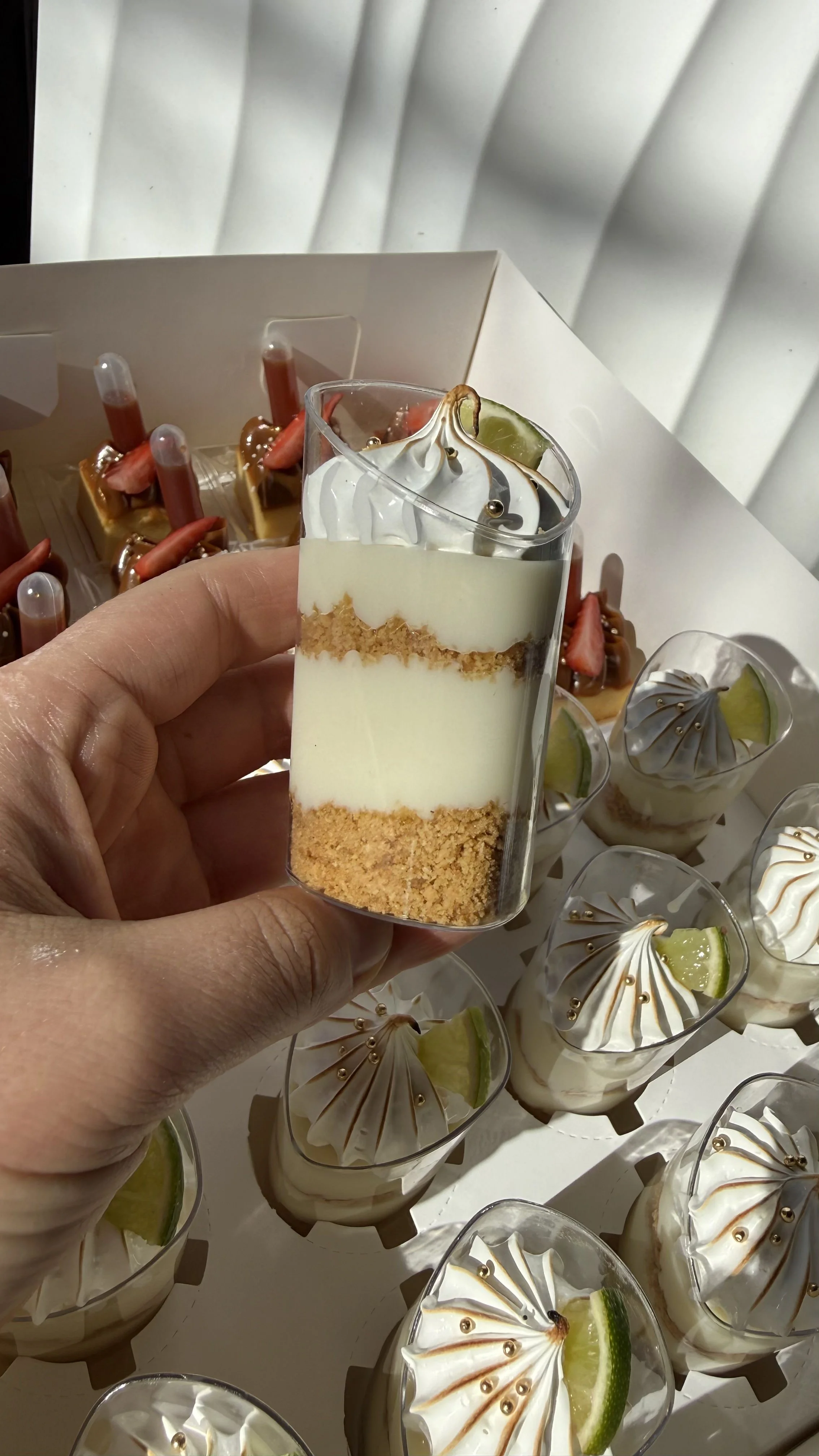 Vaso con postre de capas blancas y doradas, decorado con una rodaja de limón.