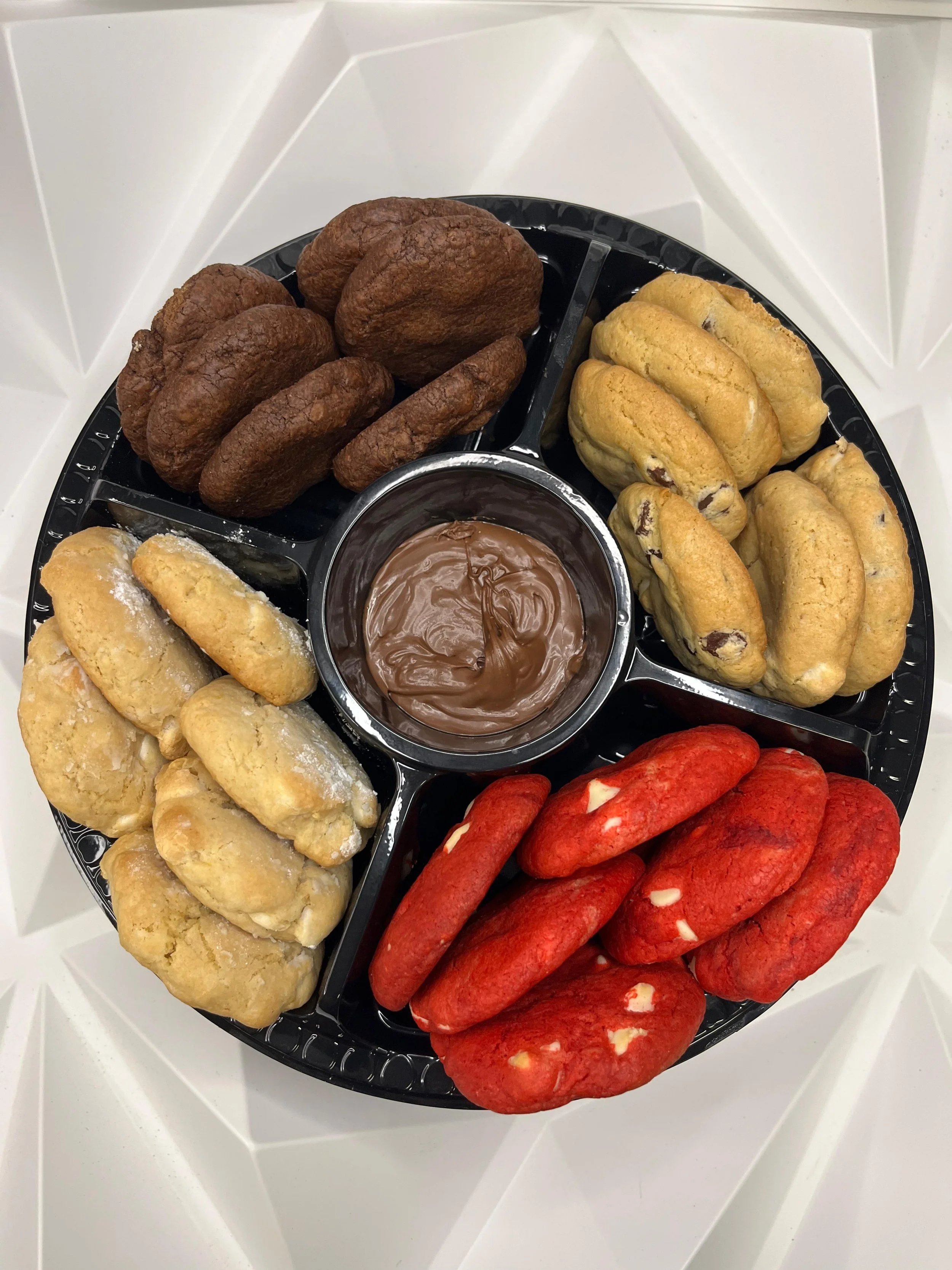 Una bandeja con diferentes tipos de galletas y un recipiente con chocolate para untar.