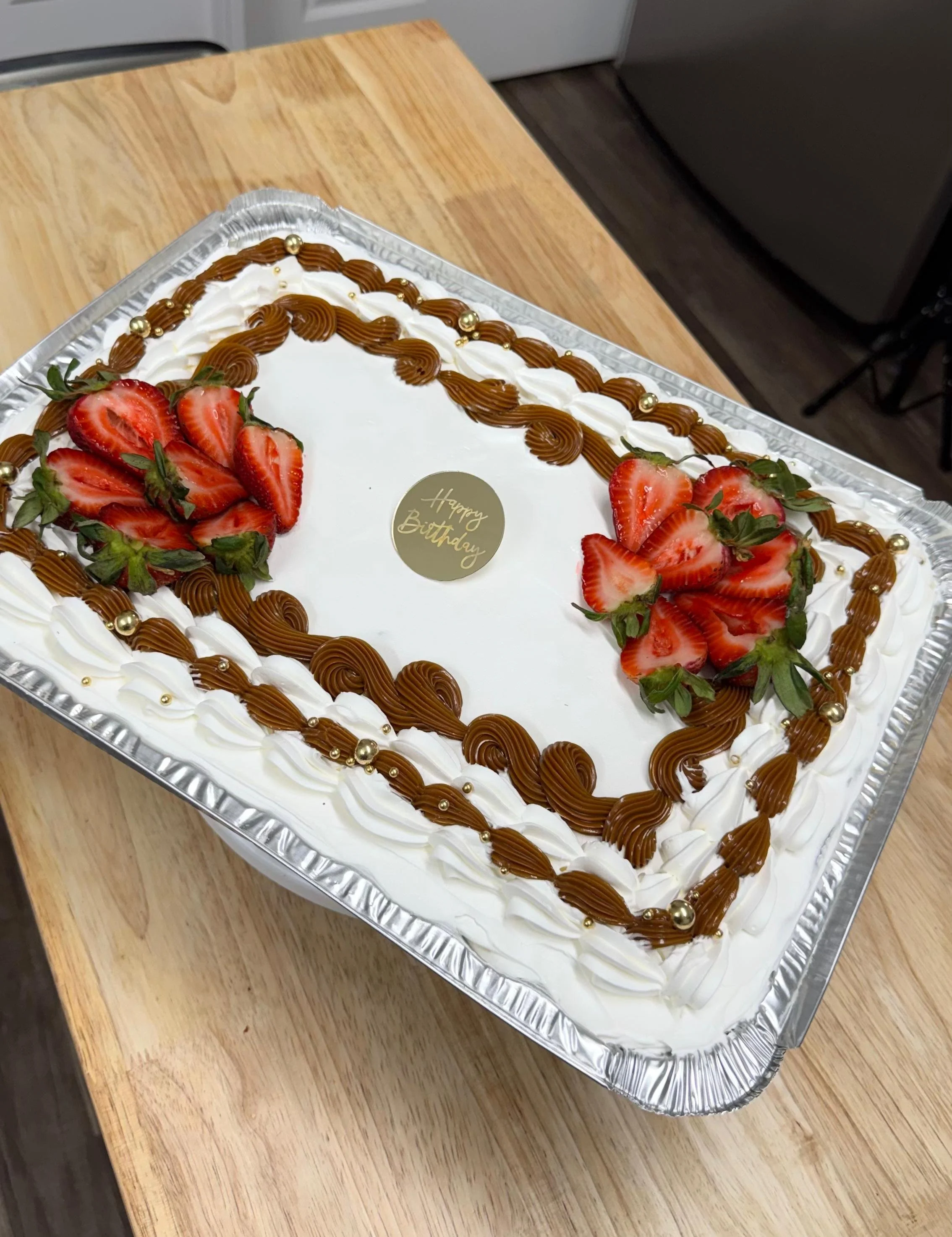 Pastel de cumpleaños rectangular decorado con fresas, crema y chocolate