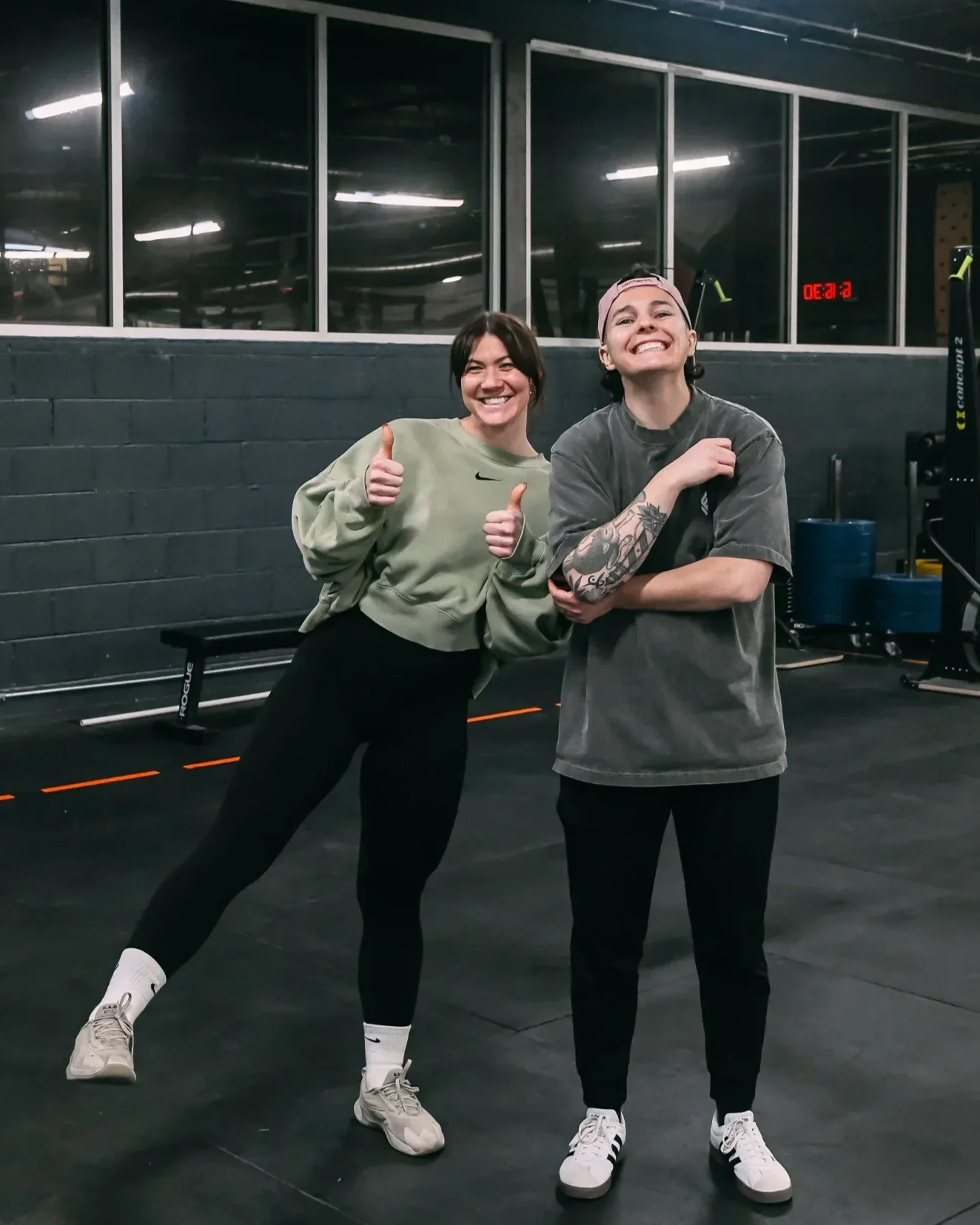 Two female coaches smiling with one giving the thumbs up to athletes at Feast Fitness in Chicago
