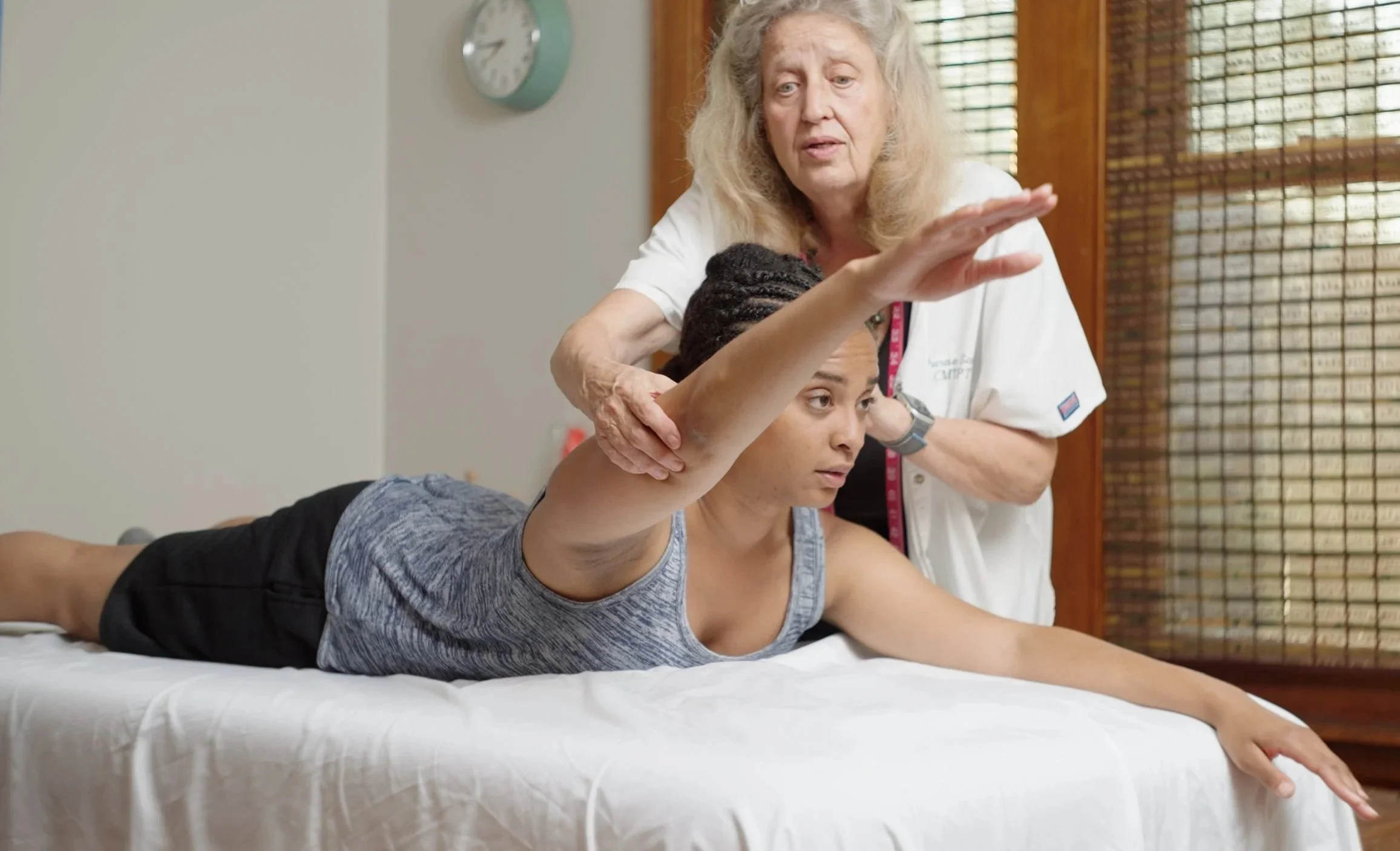 A therapist performing myofascial trigger point therapy on a woman lying on her back.