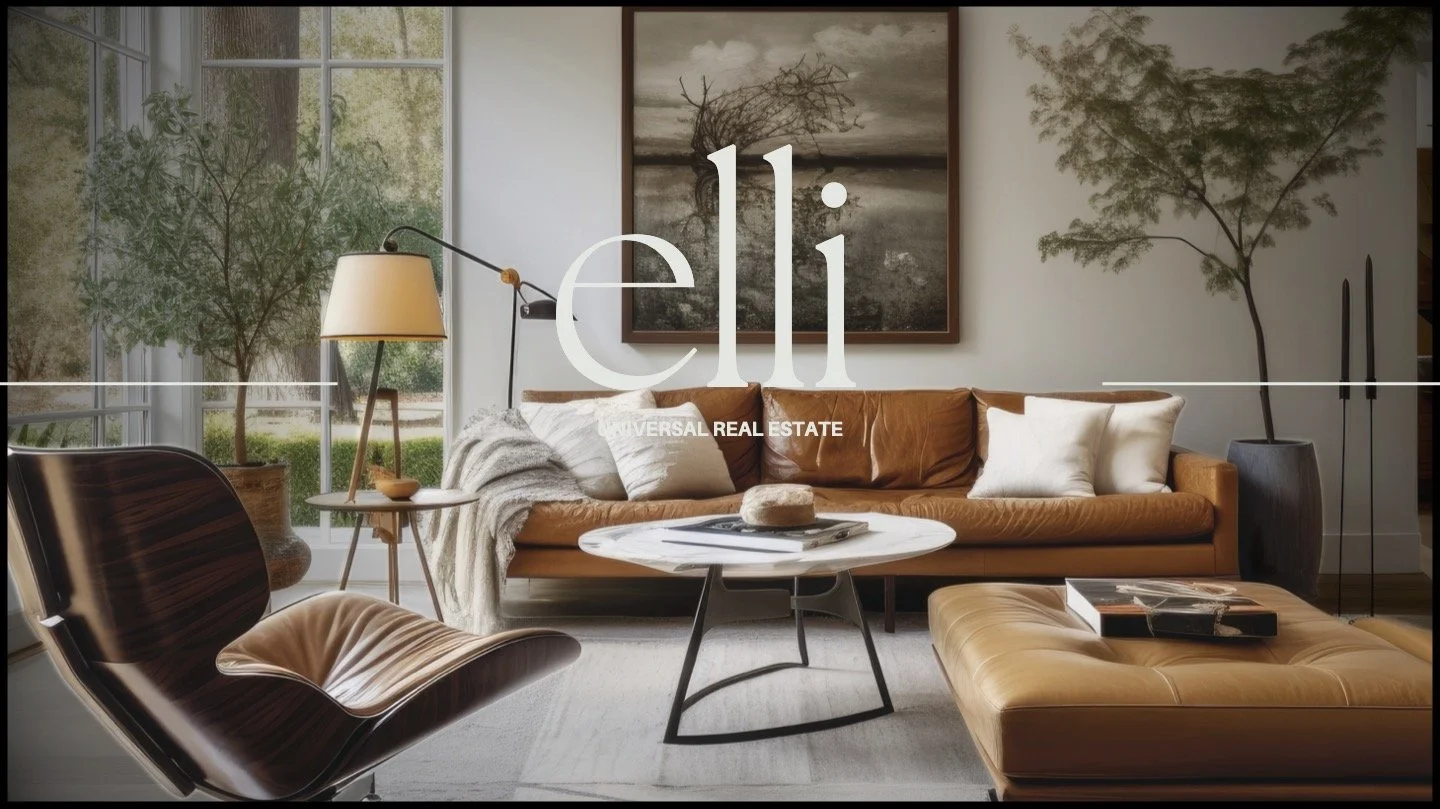 A modern living room with large windows, a tan leather sofa, an armchair, a white marble coffee table, and decorative plants.