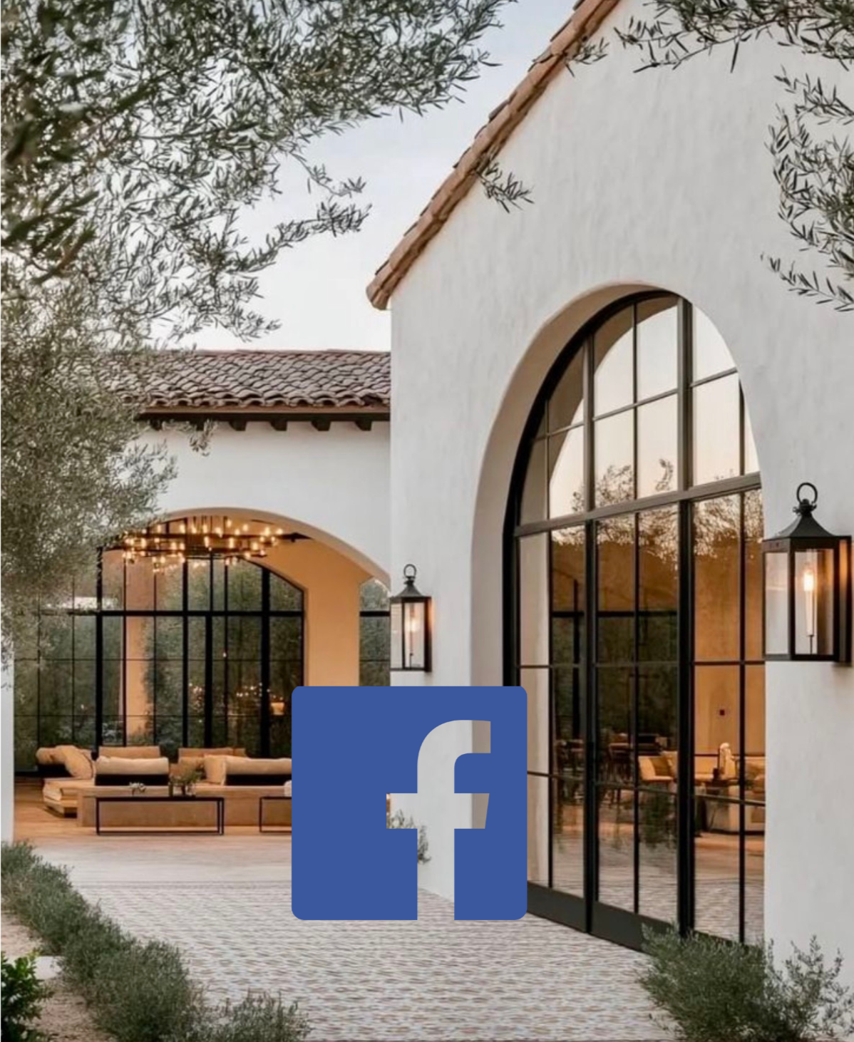 Exterior view of a modern house with large arched windows, white stucco walls, and a red tile roof. There is outdoor seating with a sofa and coffee table, decorative lights, and two wall-mounted lanterns. The scene is captured during dusk or early evening with trees and shrubs in the background, and a Facebook logo overlayed at the bottom.