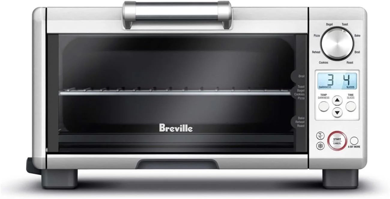 A stainless steel Breville toaster oven with digital controls and a display showing temperature and toasting time.