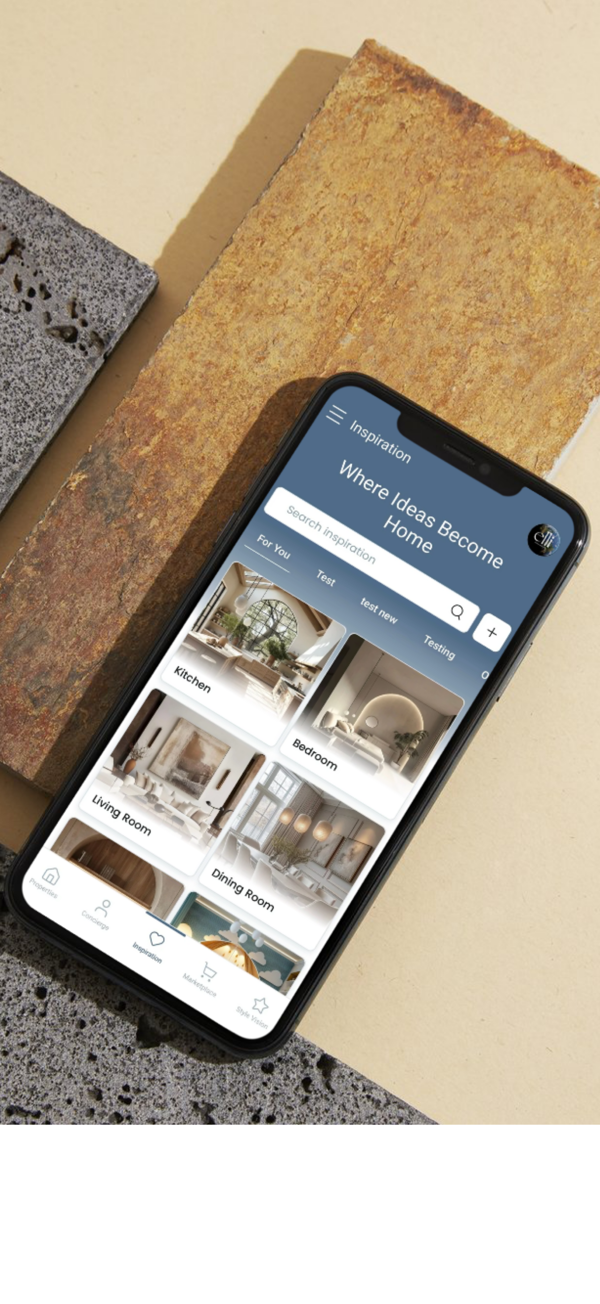 Smartphone displaying a home design inspiration app with categories for kitchen, bedroom, living room, and dining room, resting on textured stone and brick surfaces.