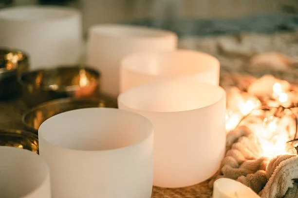A collection of white and gold tea light candle holders on a surface, some lit and others unlit.
