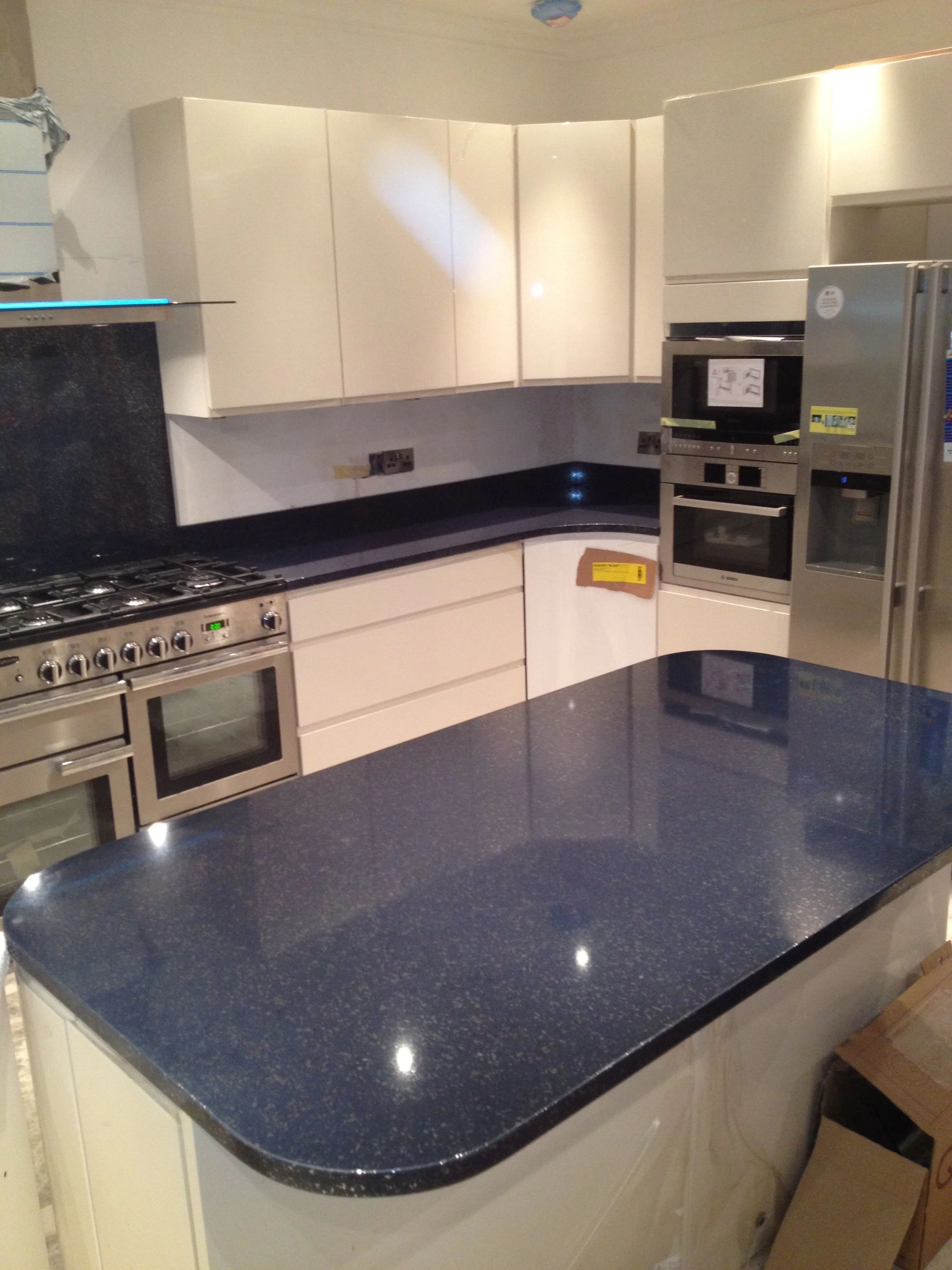 Kitchen with white cabinets, black granite countertops, stainless steel oven, microwave, and refrigerator.