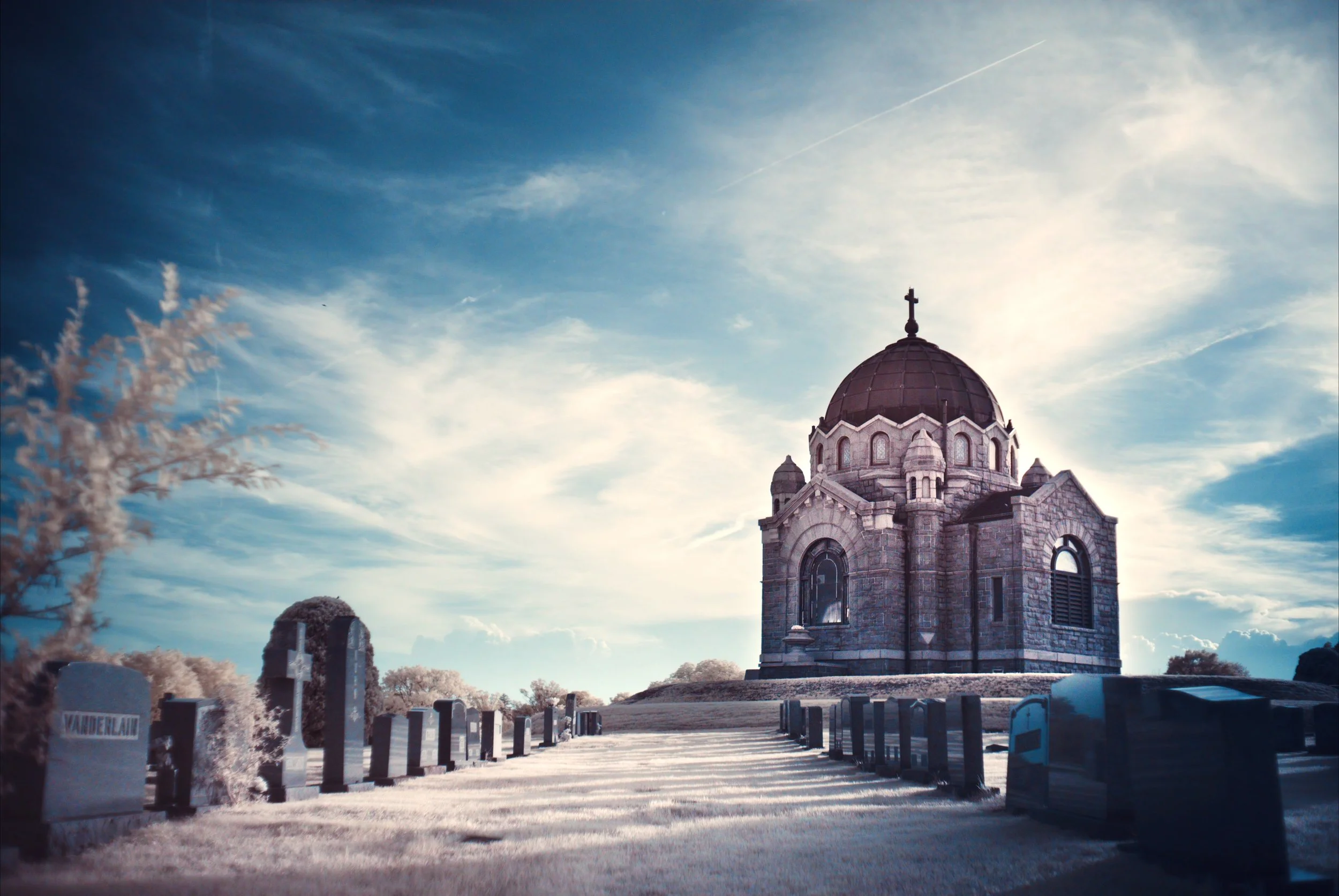 An infrared image of a cemetery with a mausoleum contrasted against a blue sky