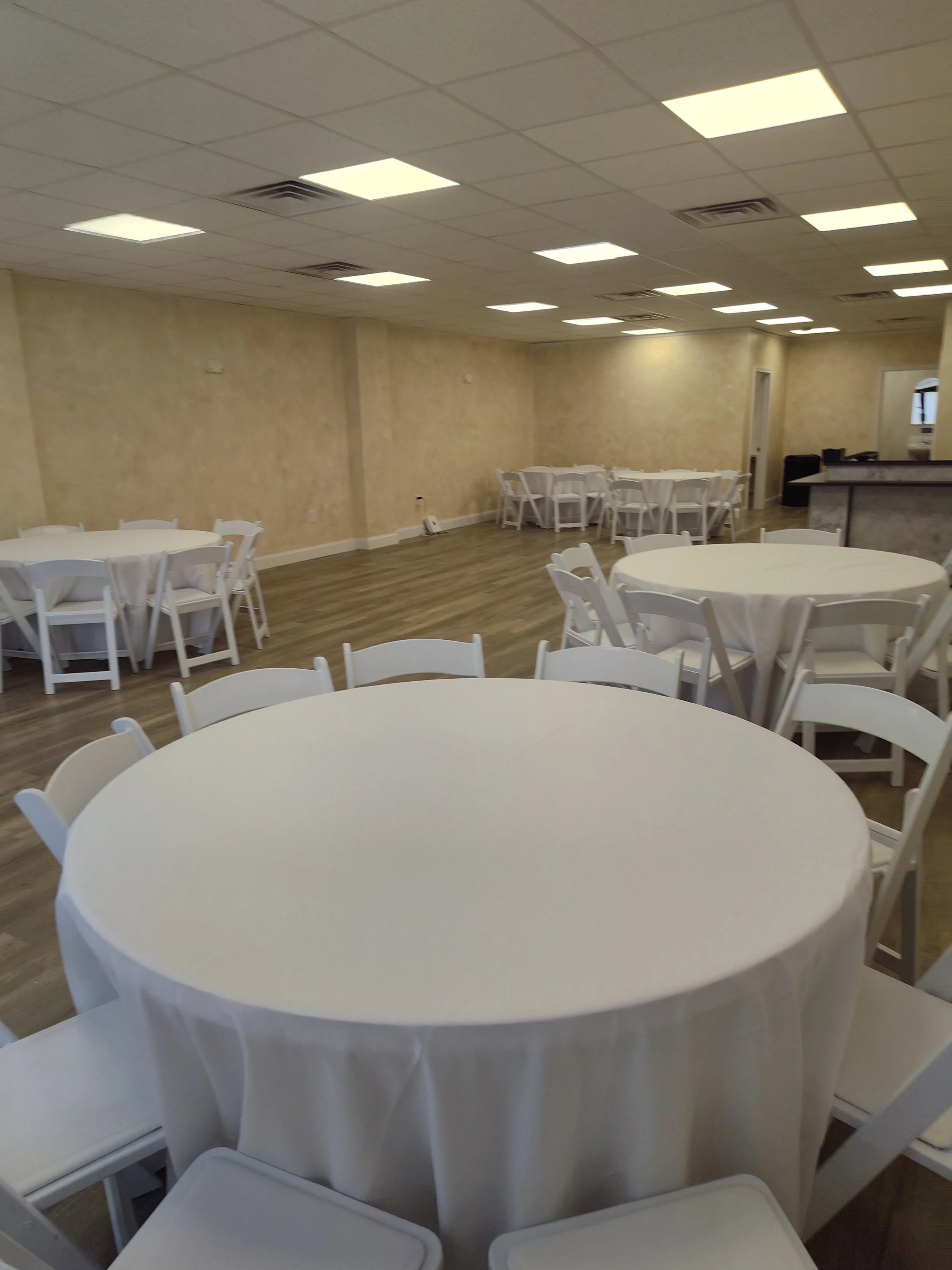 Venue with round tables, white linens and white garden chairs