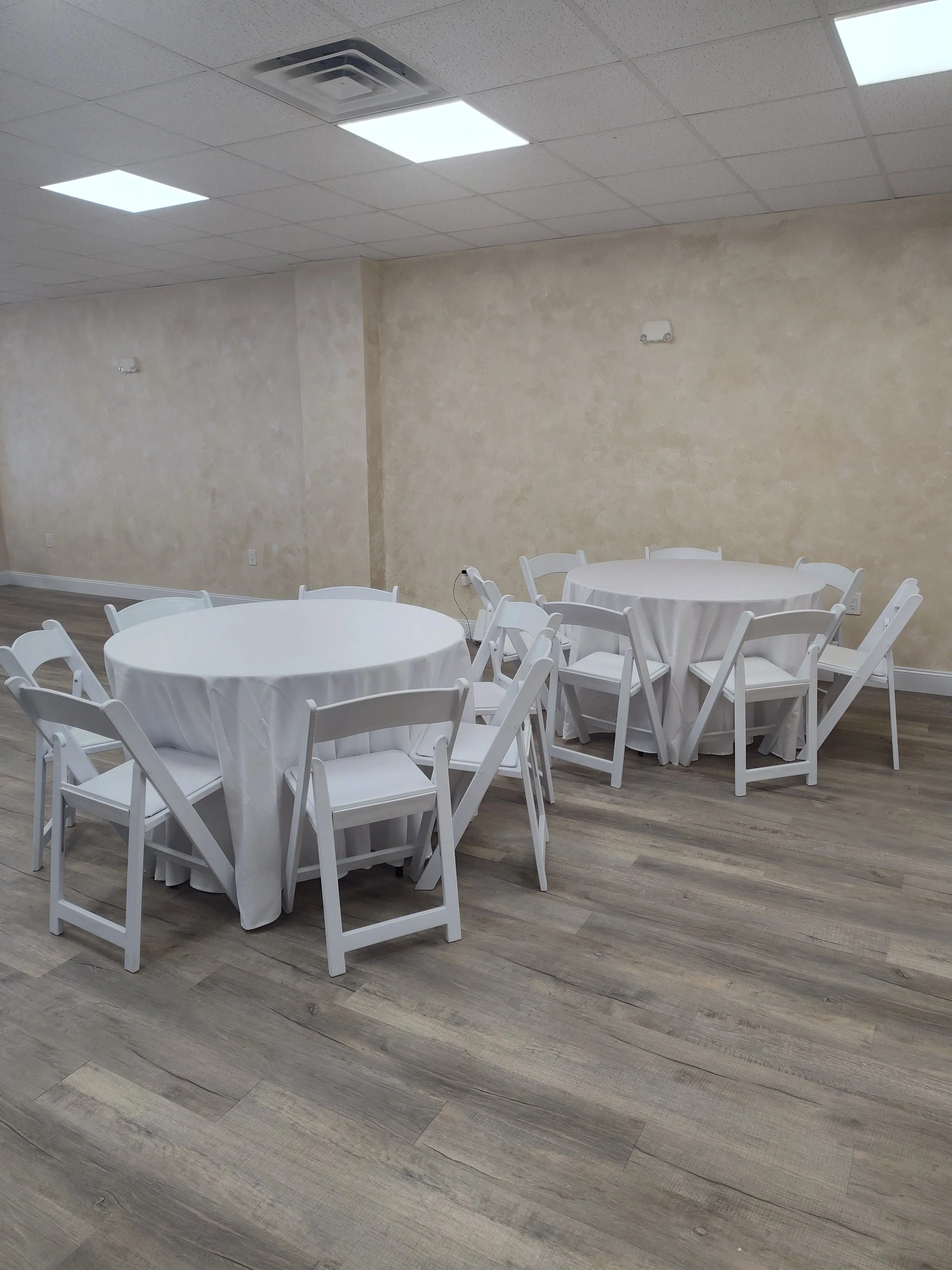 Venue with round tables, white linens and white garden chairs