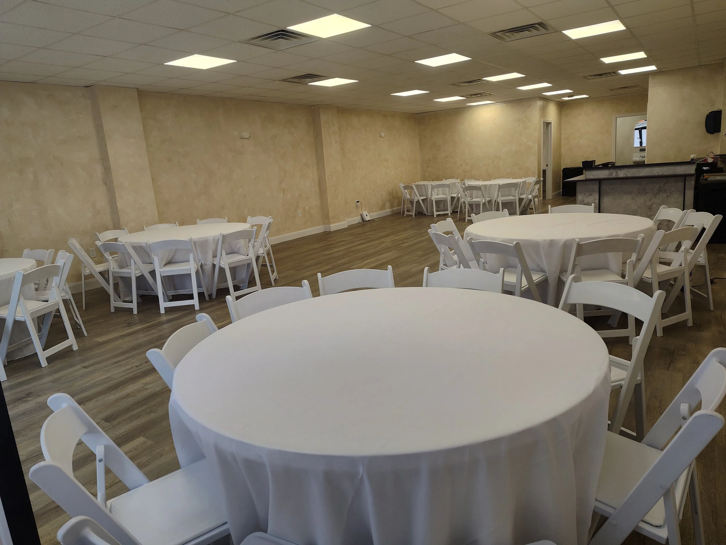 Venue with round tables, white linens and white garden chairs