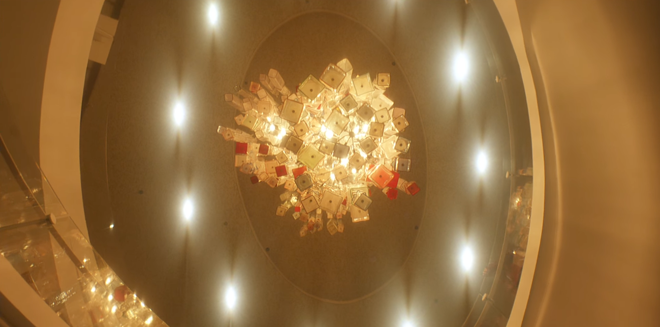 A chandelier hanging from a circular ceiling in a hotel lobby