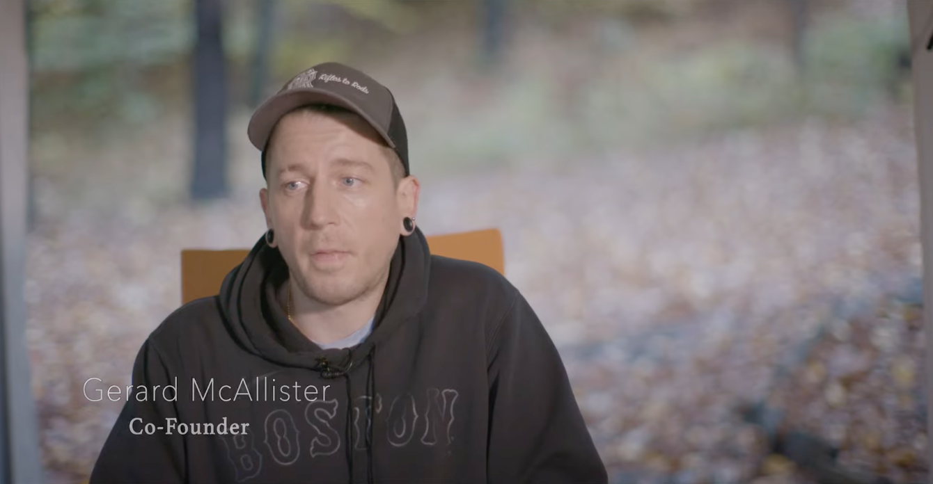 Gerard McAllister, co-founder, sitting indoors during an interview with a blurred outdoor background visible through a window.