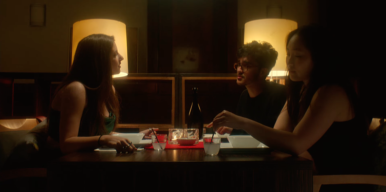 Three people having dinner at a table in a dimly lit restaurant.