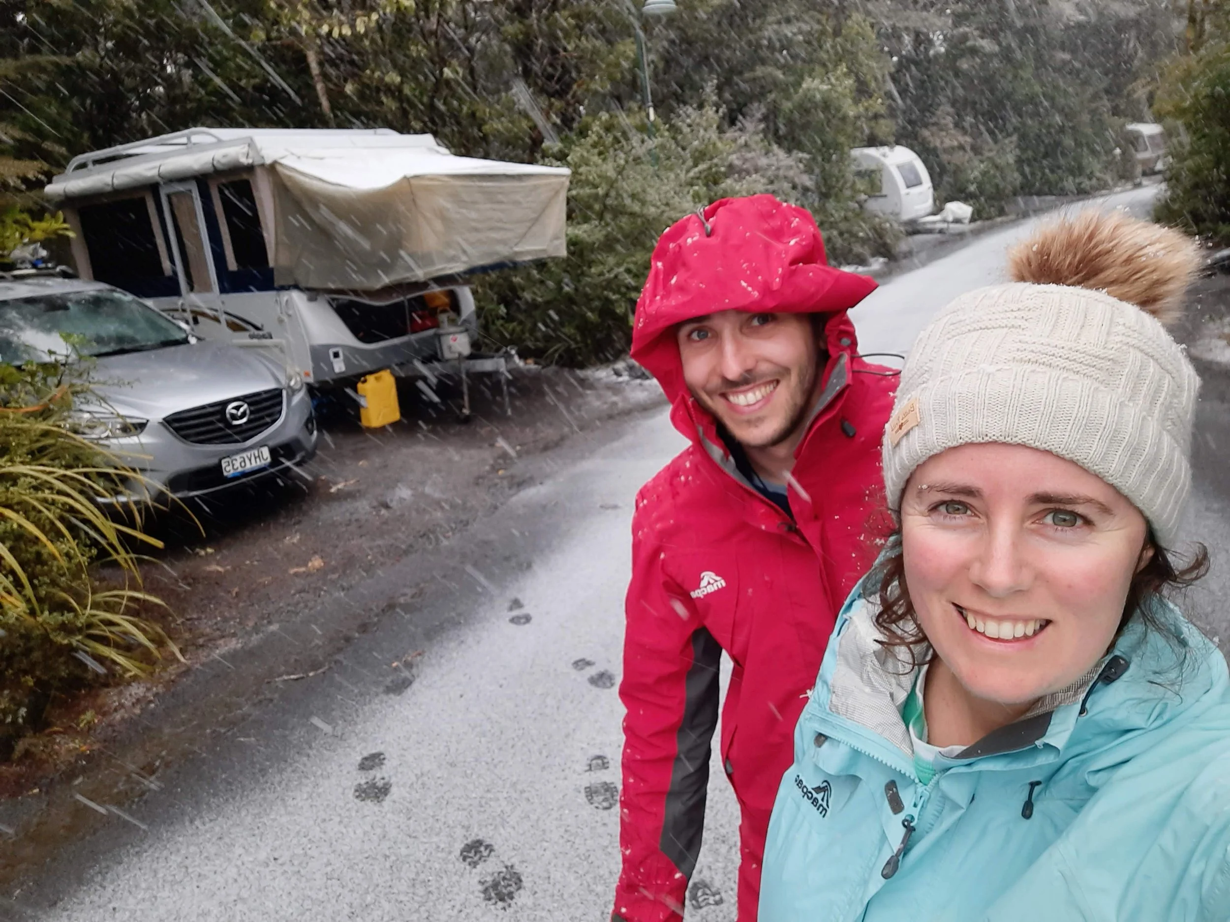 two smiling people going on a mid winter camping adventure in a campervan