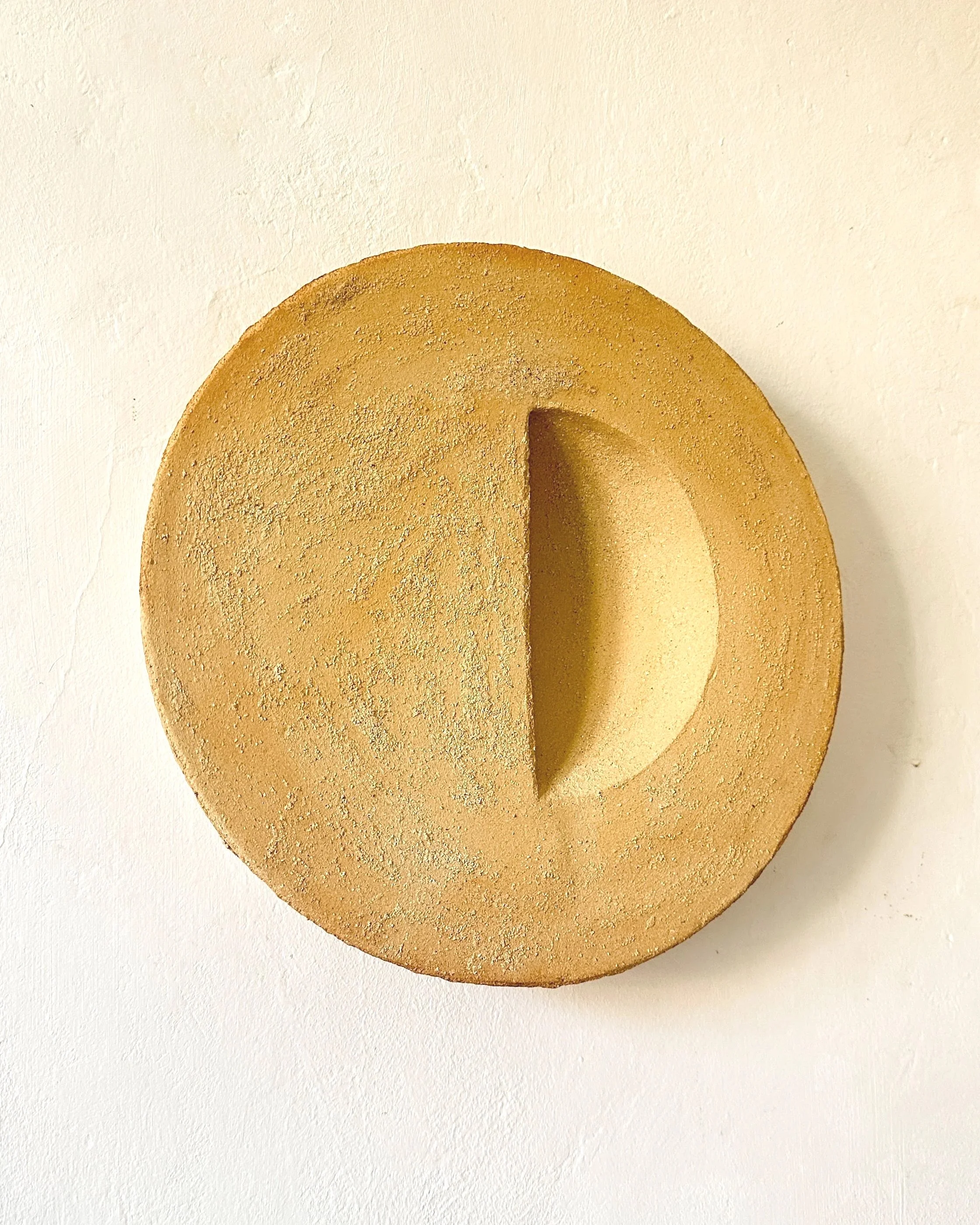 Un gâteau rond sans décoration avec une texture légèrement granuleuse, posé sur une surface blanche.