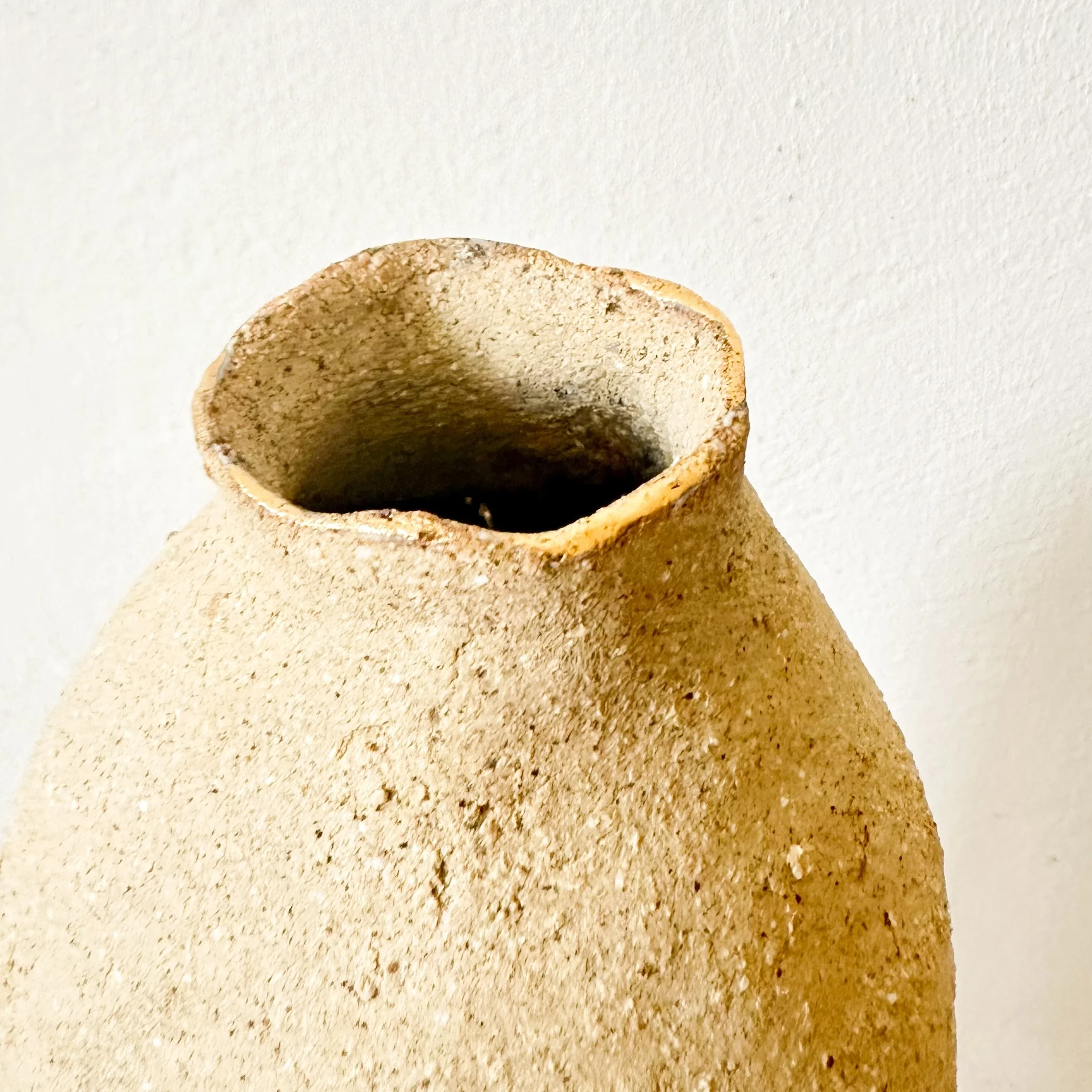 Vue rapprochée d'un bord d'un objet en céramique ou en pierre, posé sur une surface en granite ou en marbre, avec un fond blanc.