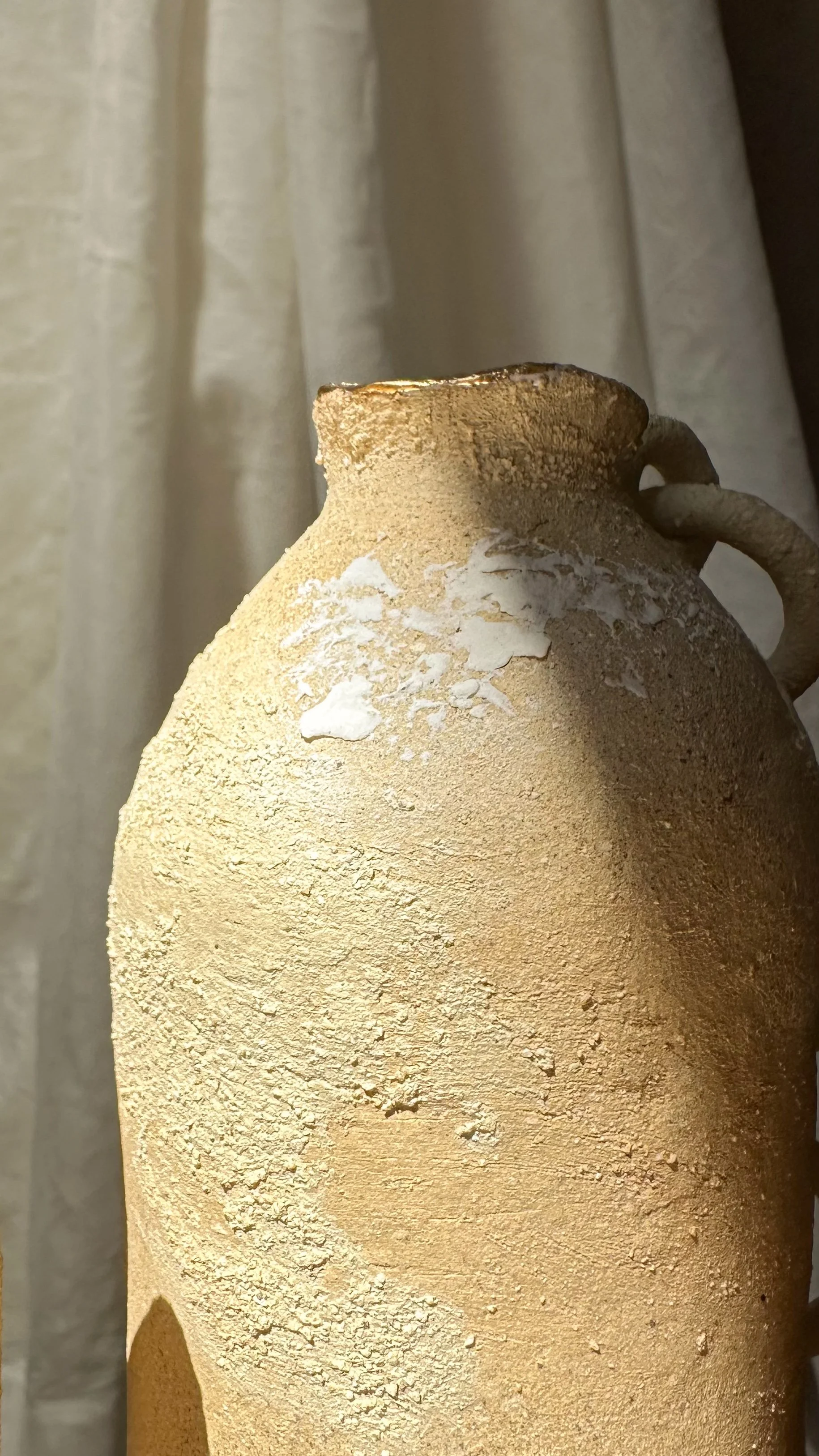 Vase en terre cuite beige avec des éclats de peinture blanche