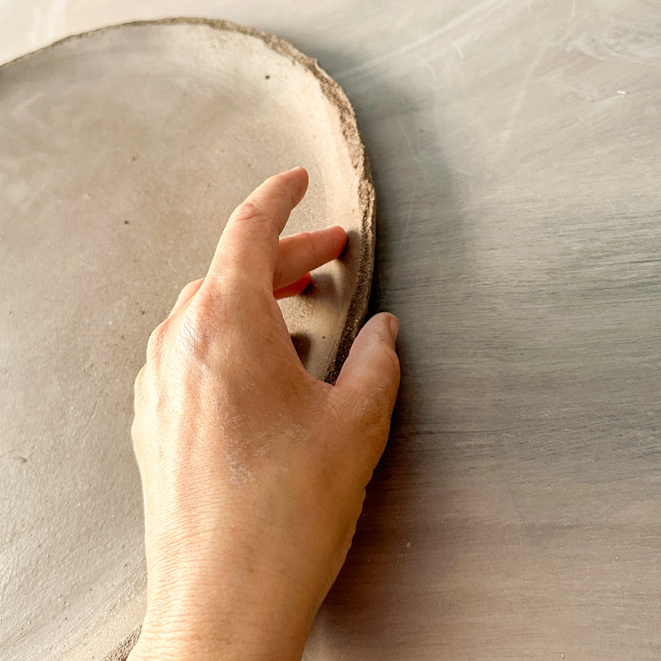 Une main touche une surface arrondie avec un bord rugueux, avec une surface plate au fond.