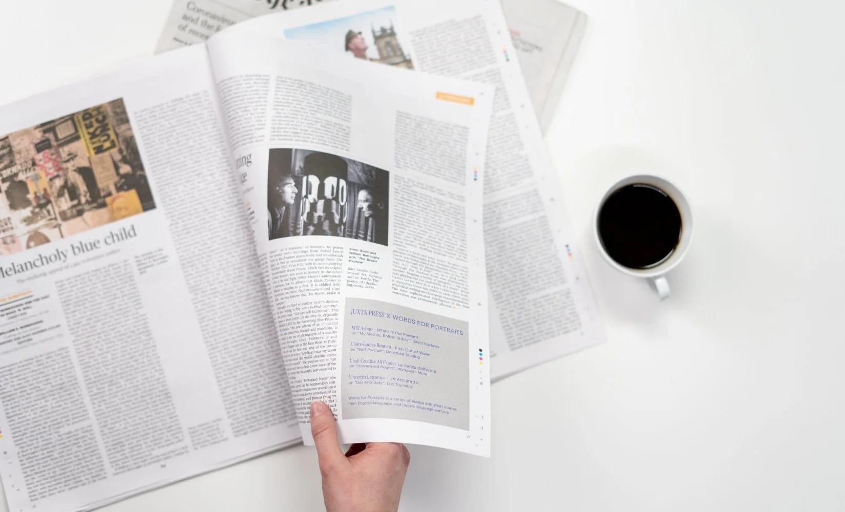 Person reads local newspaper while drinking coffee